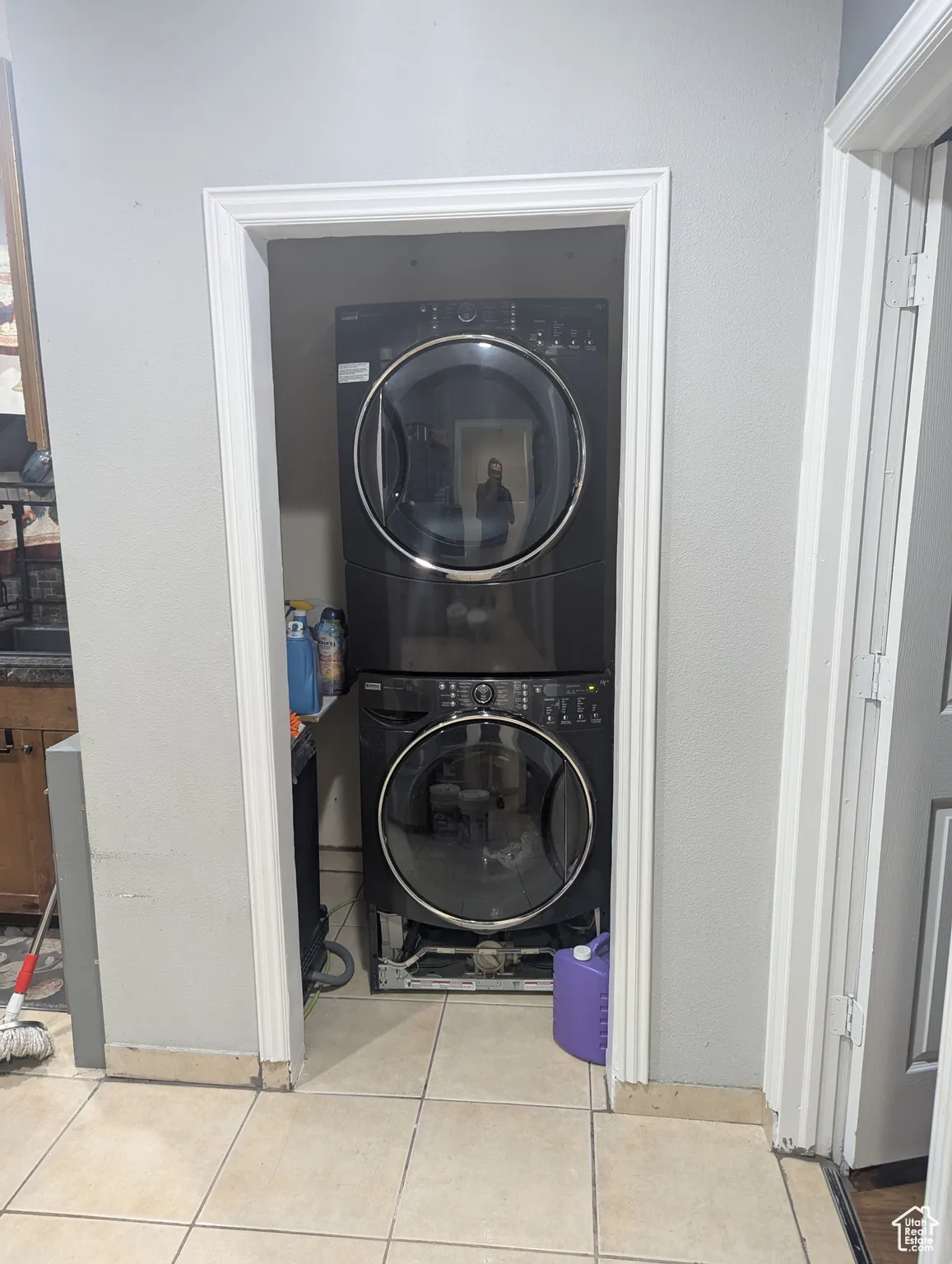 Laundry room with light tile patterned floors and stacked washer / dryer