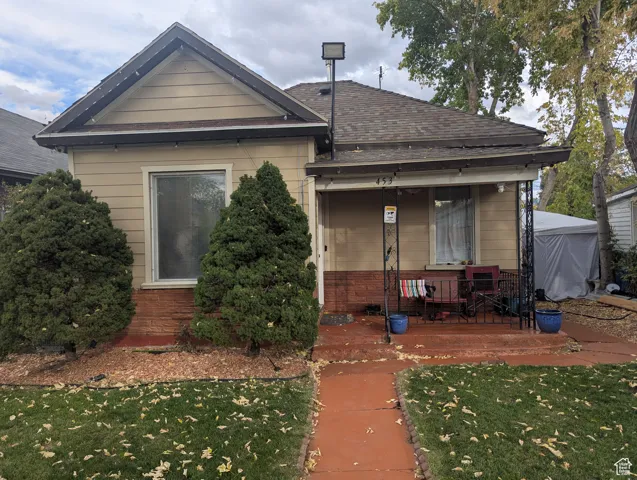 View of front of property featuring a front yard, a porch, roof with shingles, and brick siding