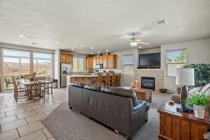 Living area with a tiled fireplace, recessed lighting, a ceiling fan, light tile patterned floors, and a textured ceiling