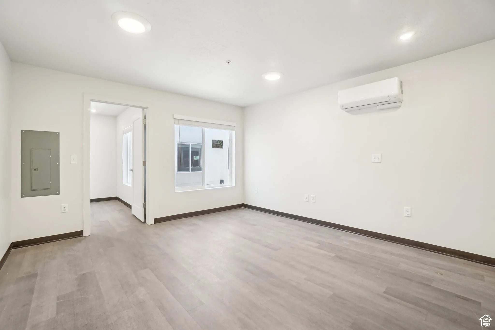Spare room featuring electric panel, light wood-style floors, and recessed lighting