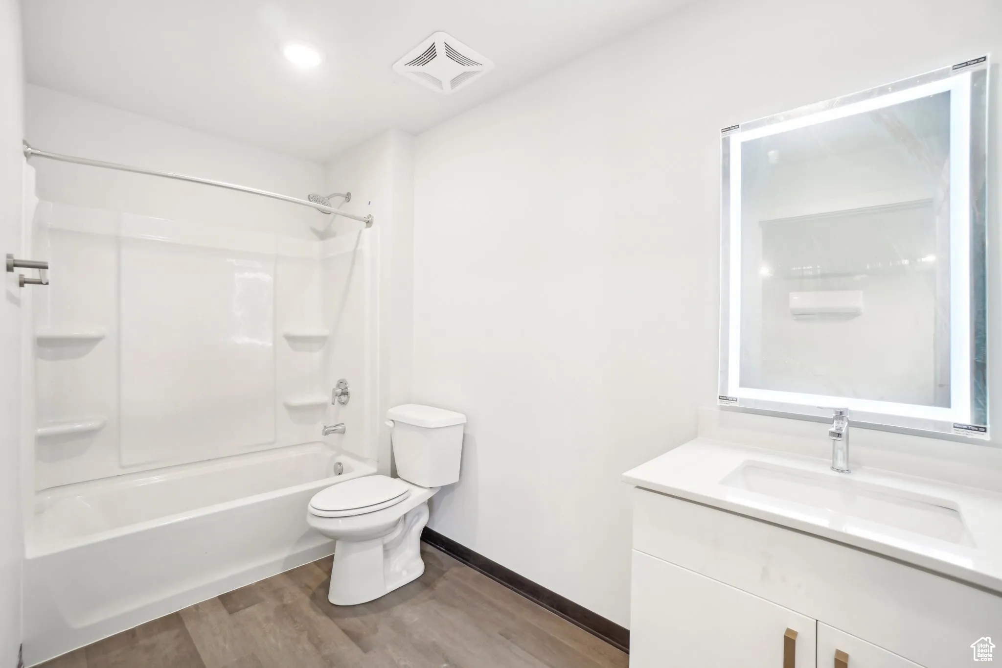 Bathroom featuring shower / washtub combination, vanity, and dark wood-style flooring
