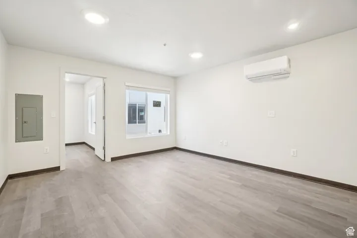 Spare room featuring electric panel, light wood-style floors, and recessed lighting