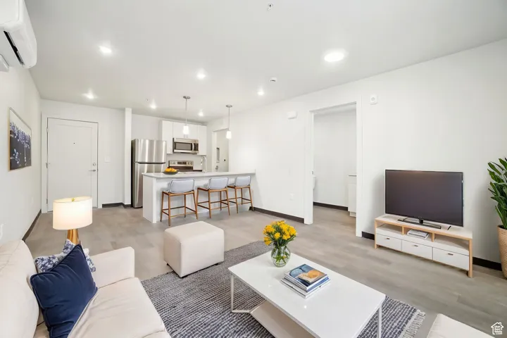 Living room with recessed lighting, a wall mounted AC, and light wood-style flooring