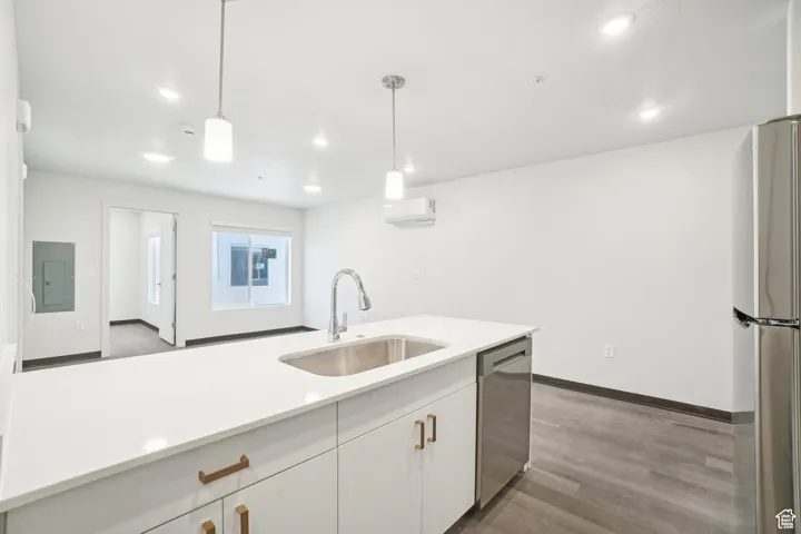 Kitchen with appliances with stainless steel finishes, dark wood-type flooring, white cabinets, hanging light fixtures, and electric panel