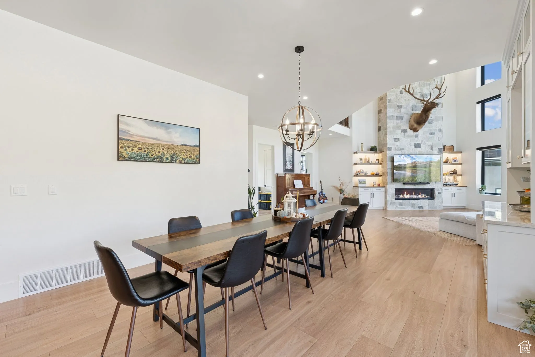 Dining room featuring light wood-type flooring, a fireplace, recessed lighting, and a chandelier