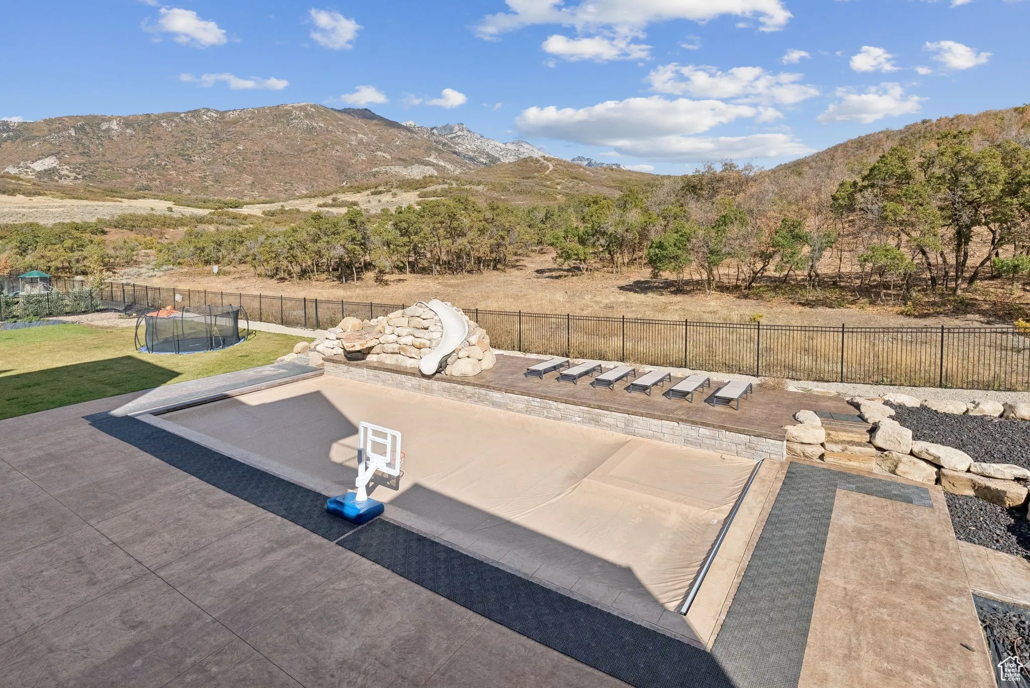 View of pool with a mountain view, a trampoline, a fenced backyard, and a water slide