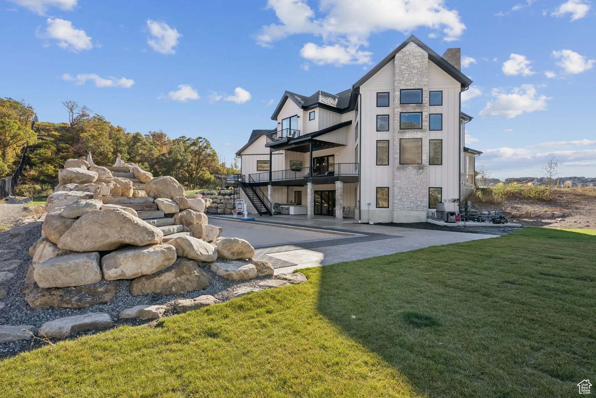Rear view of house featuring stairway, board and batten siding, a balcony, a yard, and a patio