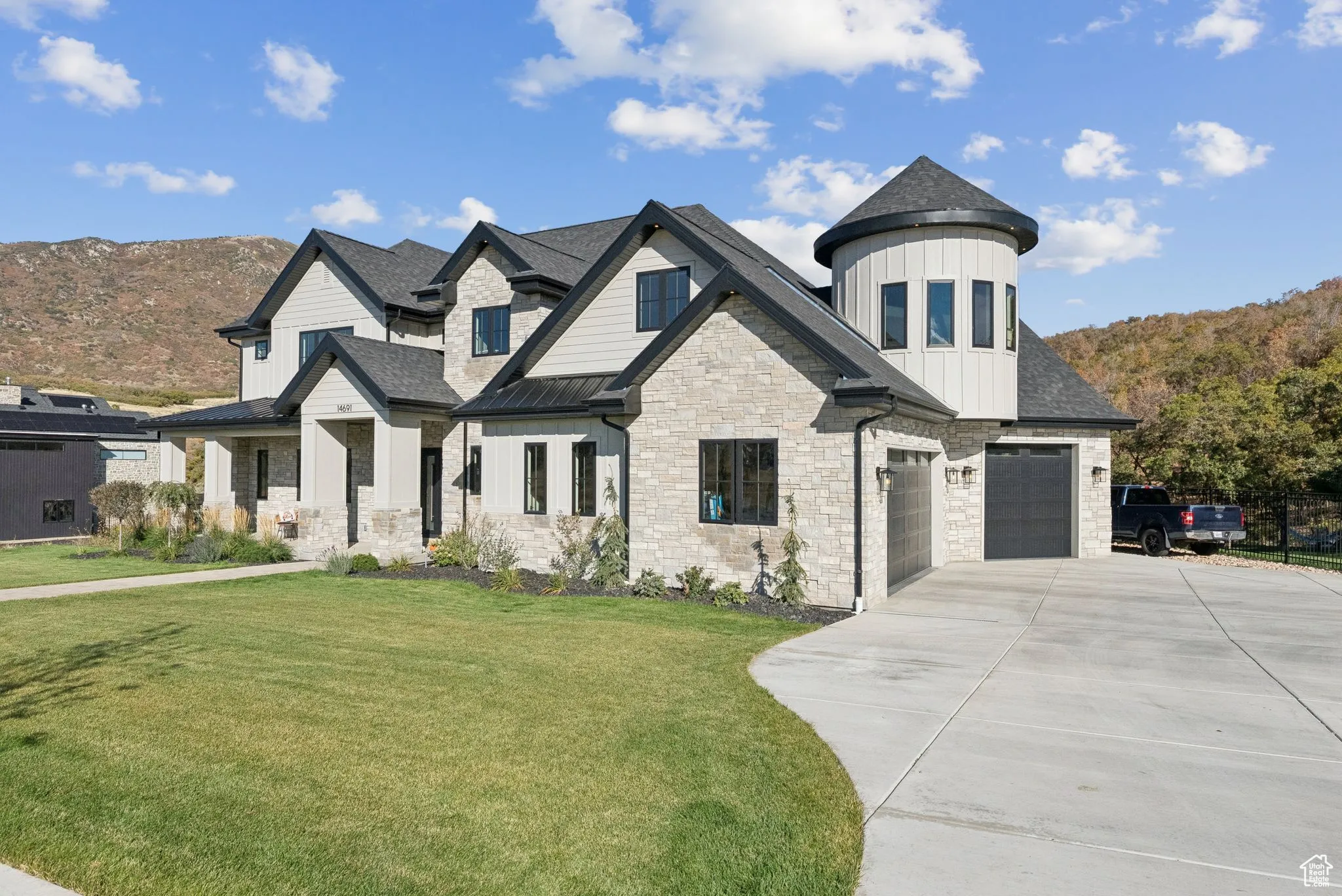 View of front of home featuring a front lawn, stone siding, board and batten siding, a standing seam roof, and concrete driveway