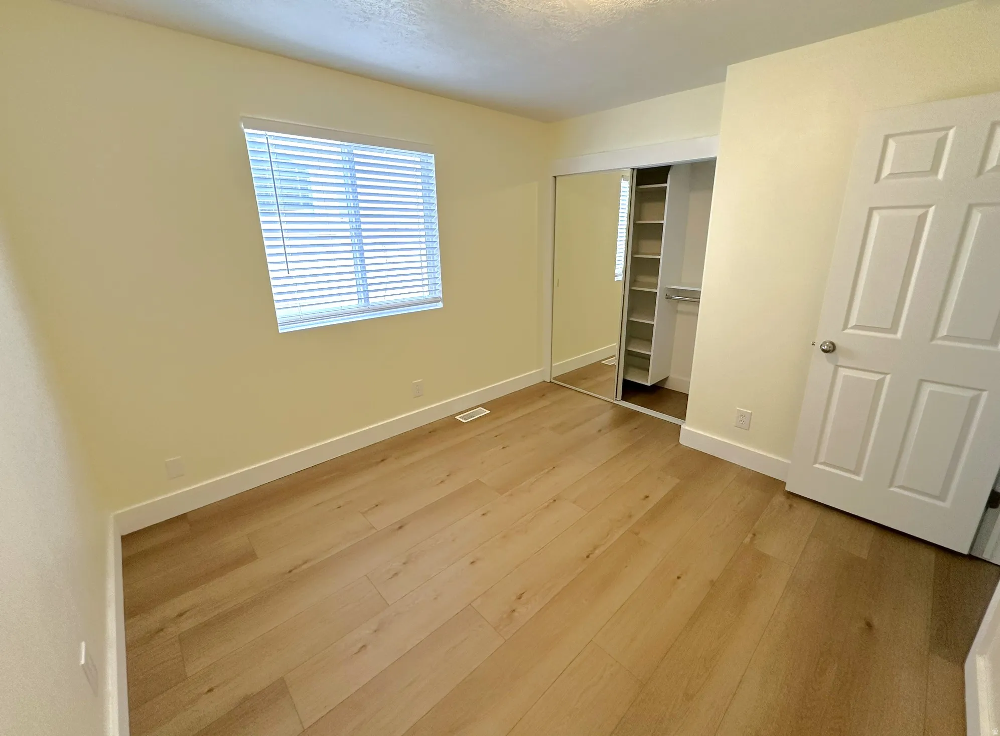 Bedroom with light wood-type flooring, a closet, and a textured ceiling