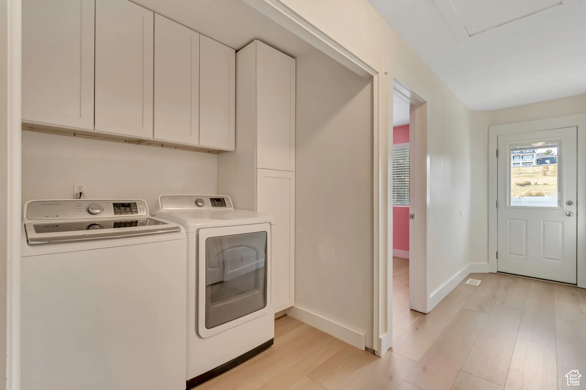 Laundry area featuring cabinet space, light wood-style floors, and washing machine and dryer