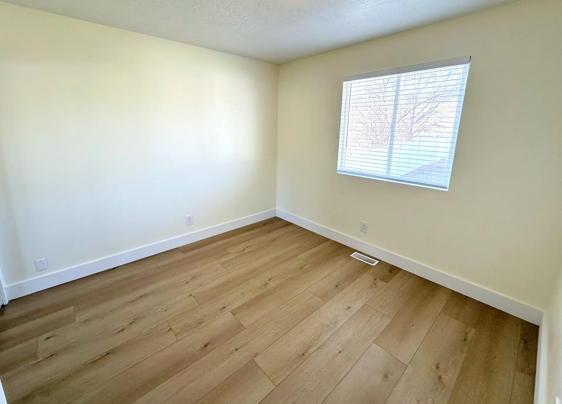 Bedroom with light wood-type flooring, a closet, and a textured ceiling