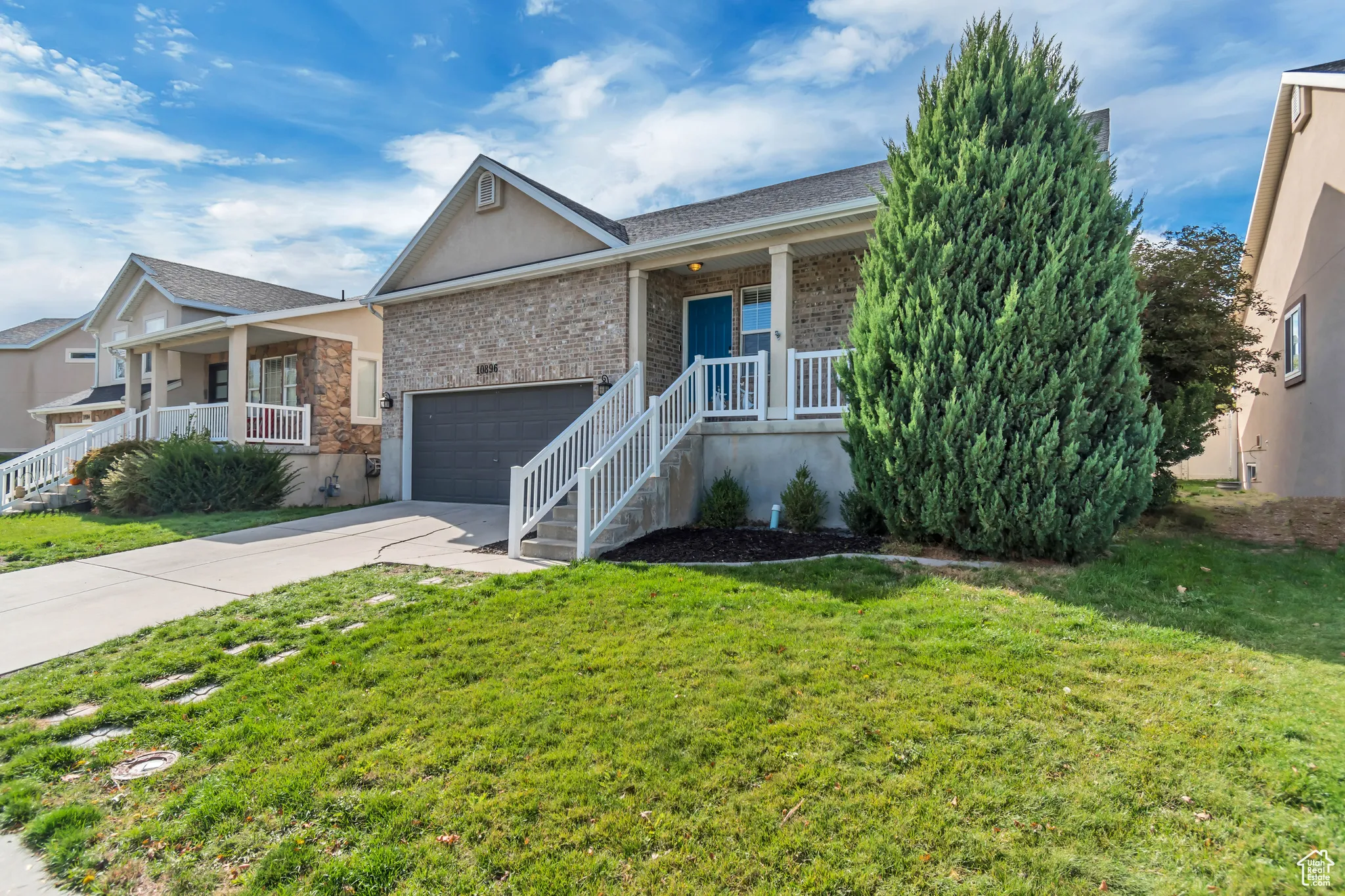 Ranch-style house with covered porch, driveway, a garage, a front yard, and brick siding