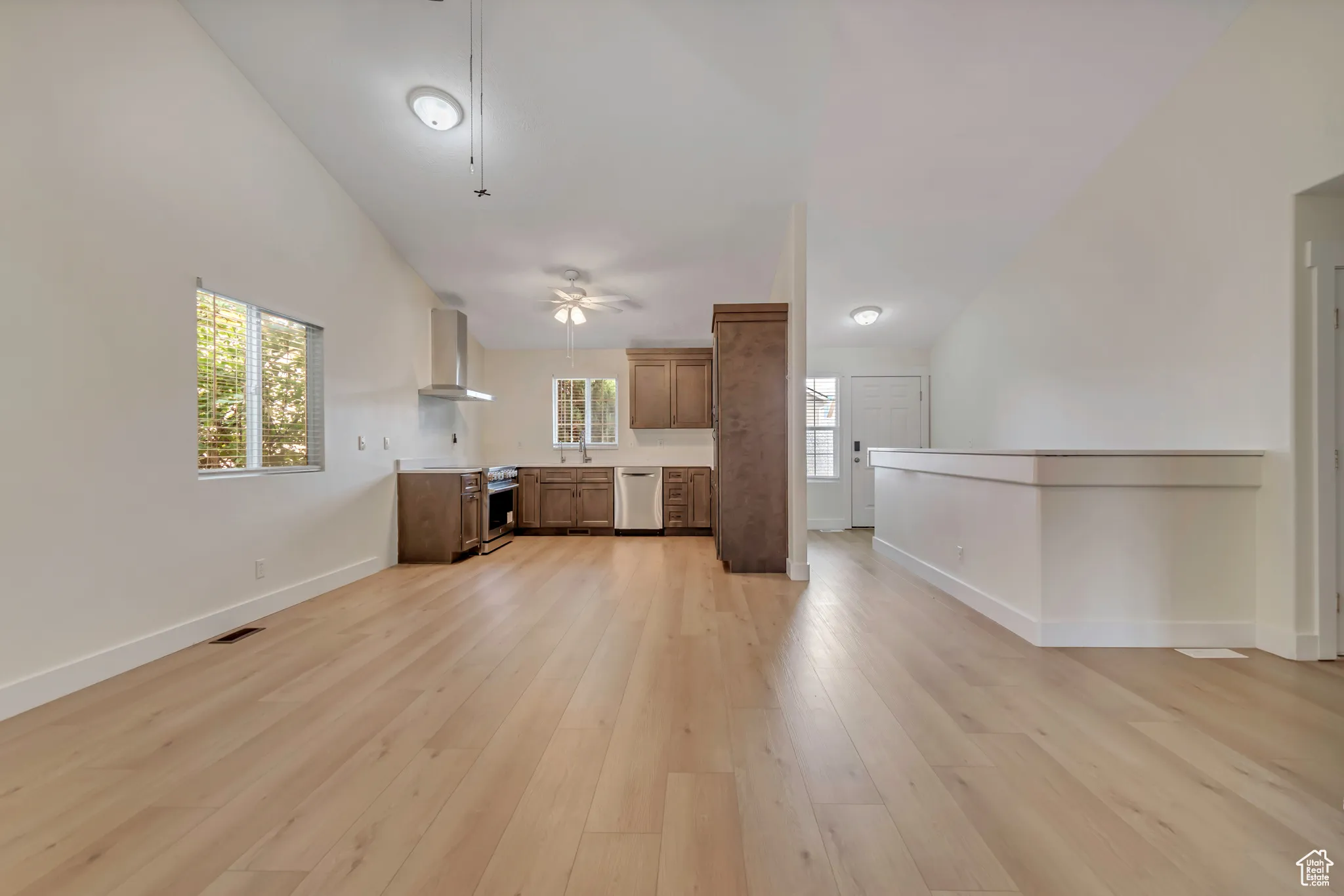 Kitchen and Dining Area featuring open floor plan, light wood-style flooring, light countertops, and high vaulted ceiling
