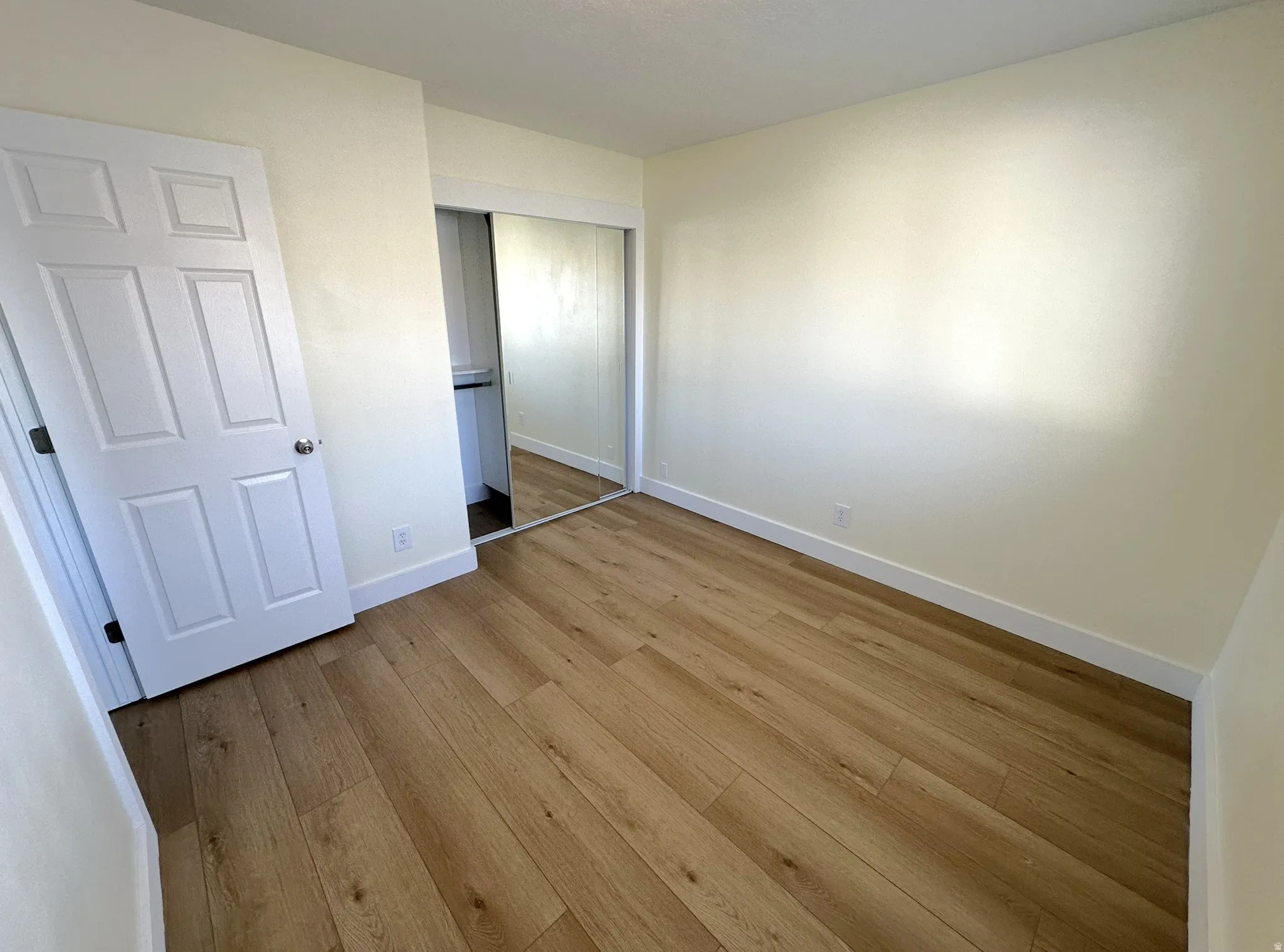 Bedroom with light wood-type flooring, a closet, and a textured ceiling