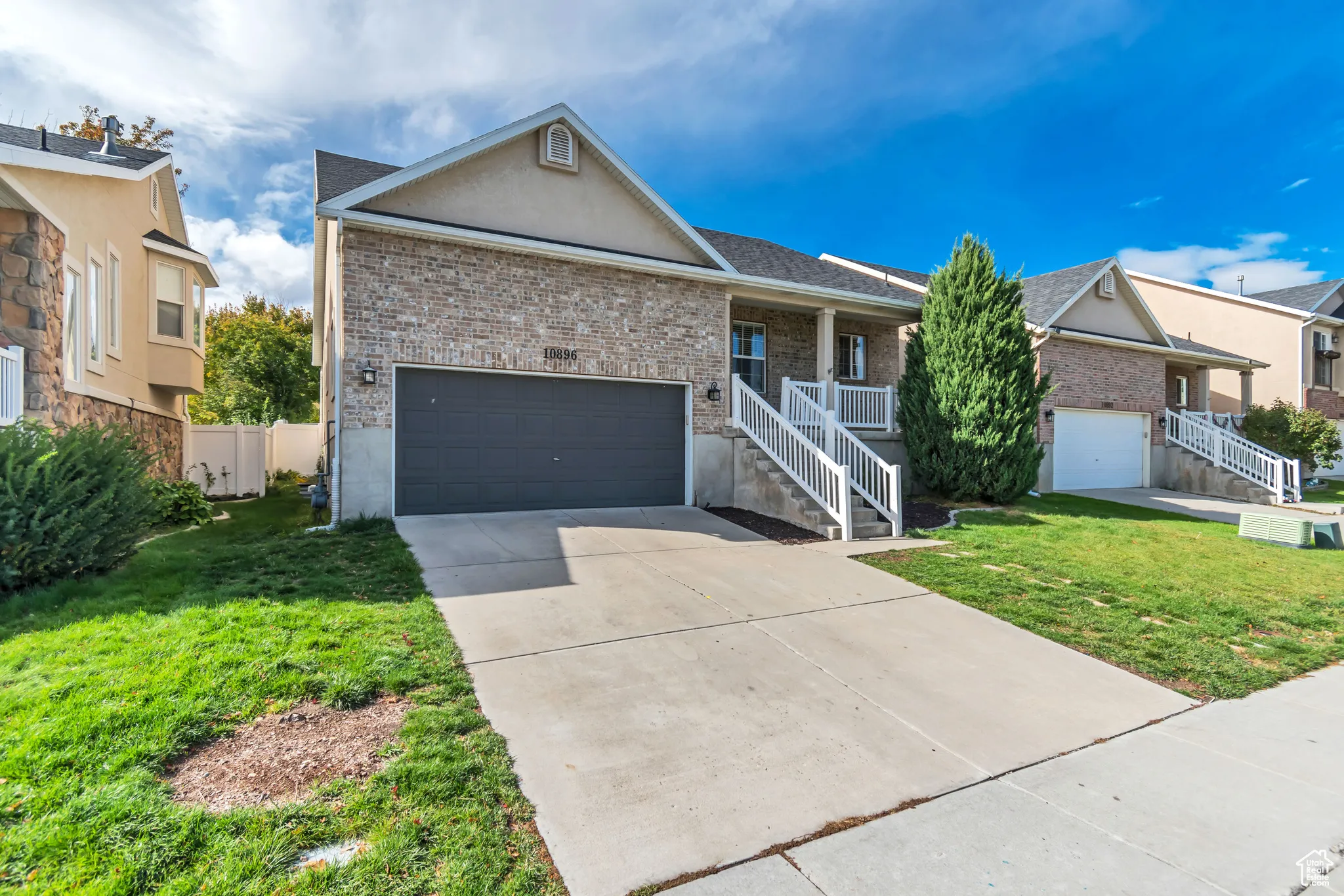 Single story home featuring a porch, concrete driveway, a garage, and brick siding