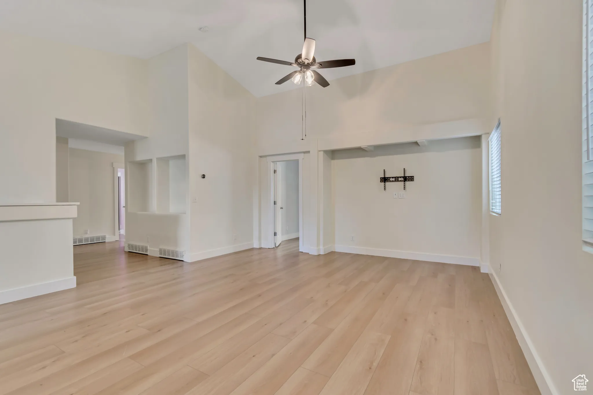 Living room featuring high vaulted ceiling, light wood-style flooring, and a ceiling fan