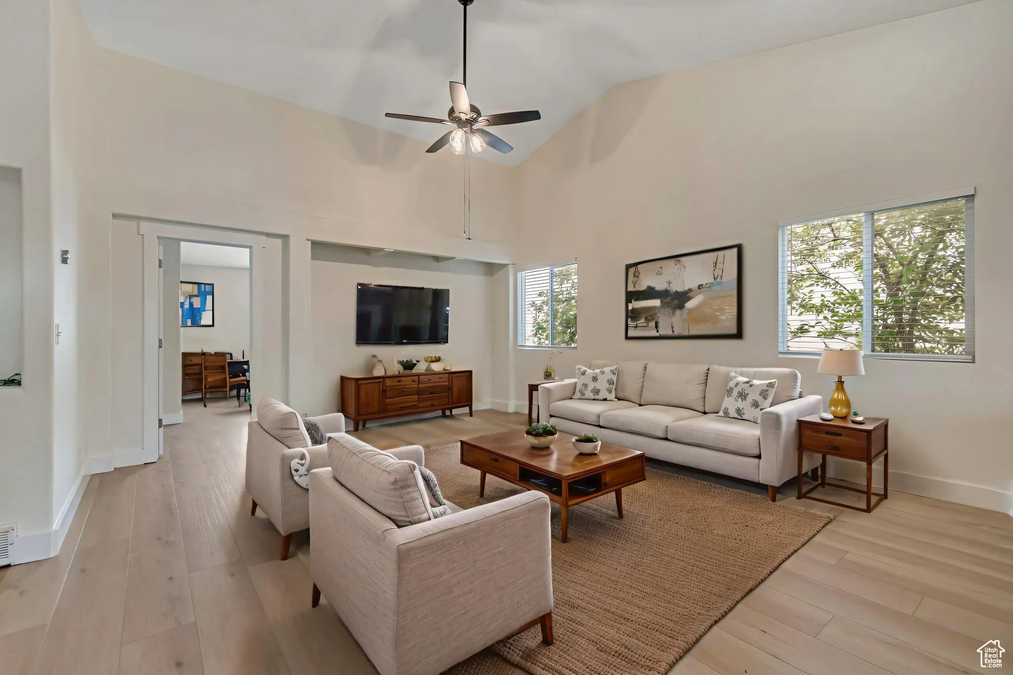 VIRTUALLY STAGED -- Living room featuring high vaulted ceiling, light wood-style flooring, and a ceiling fan