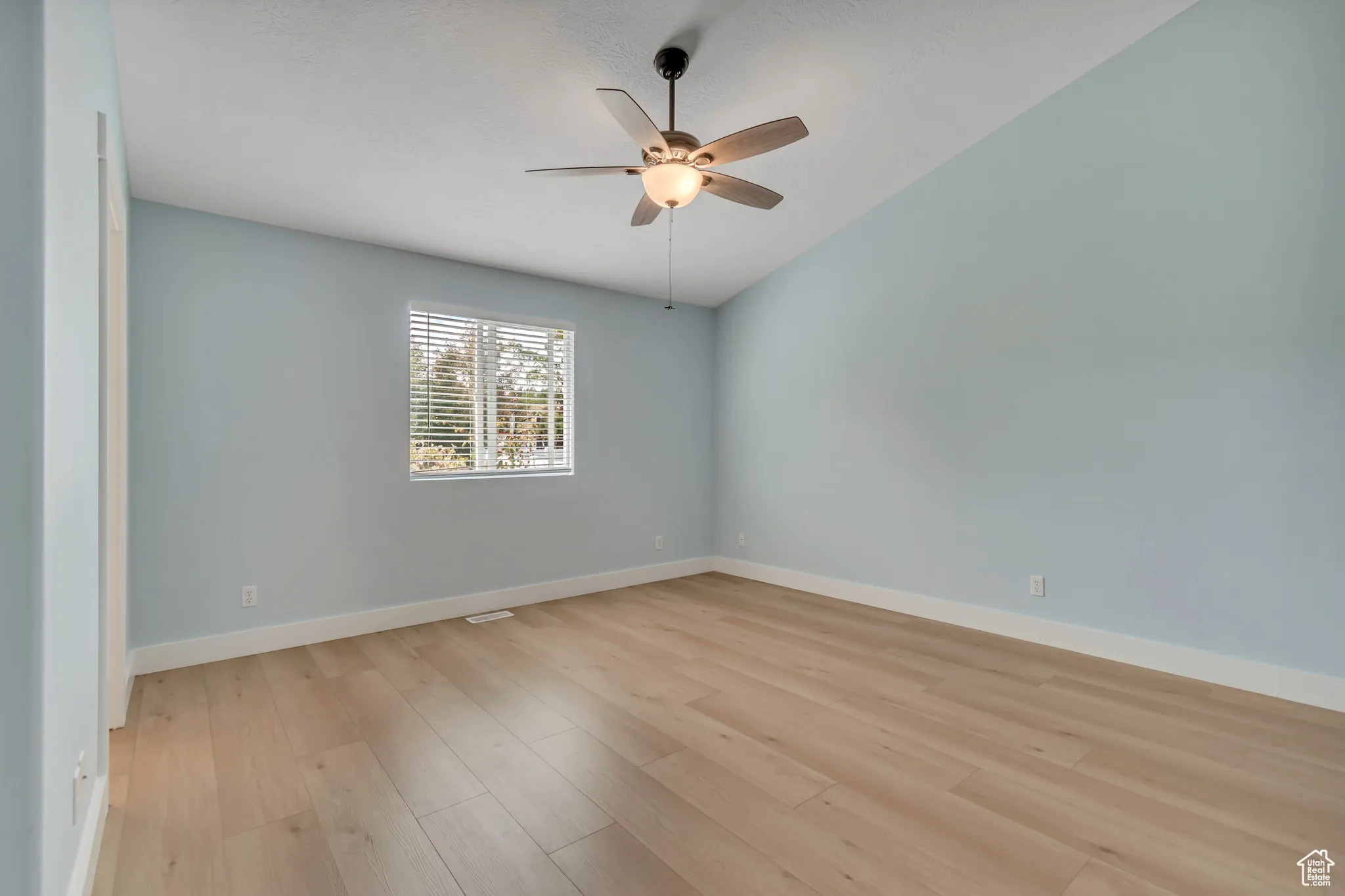 Primary bedroom with light wood-style floors, a ceiling fan, and ensuite bath