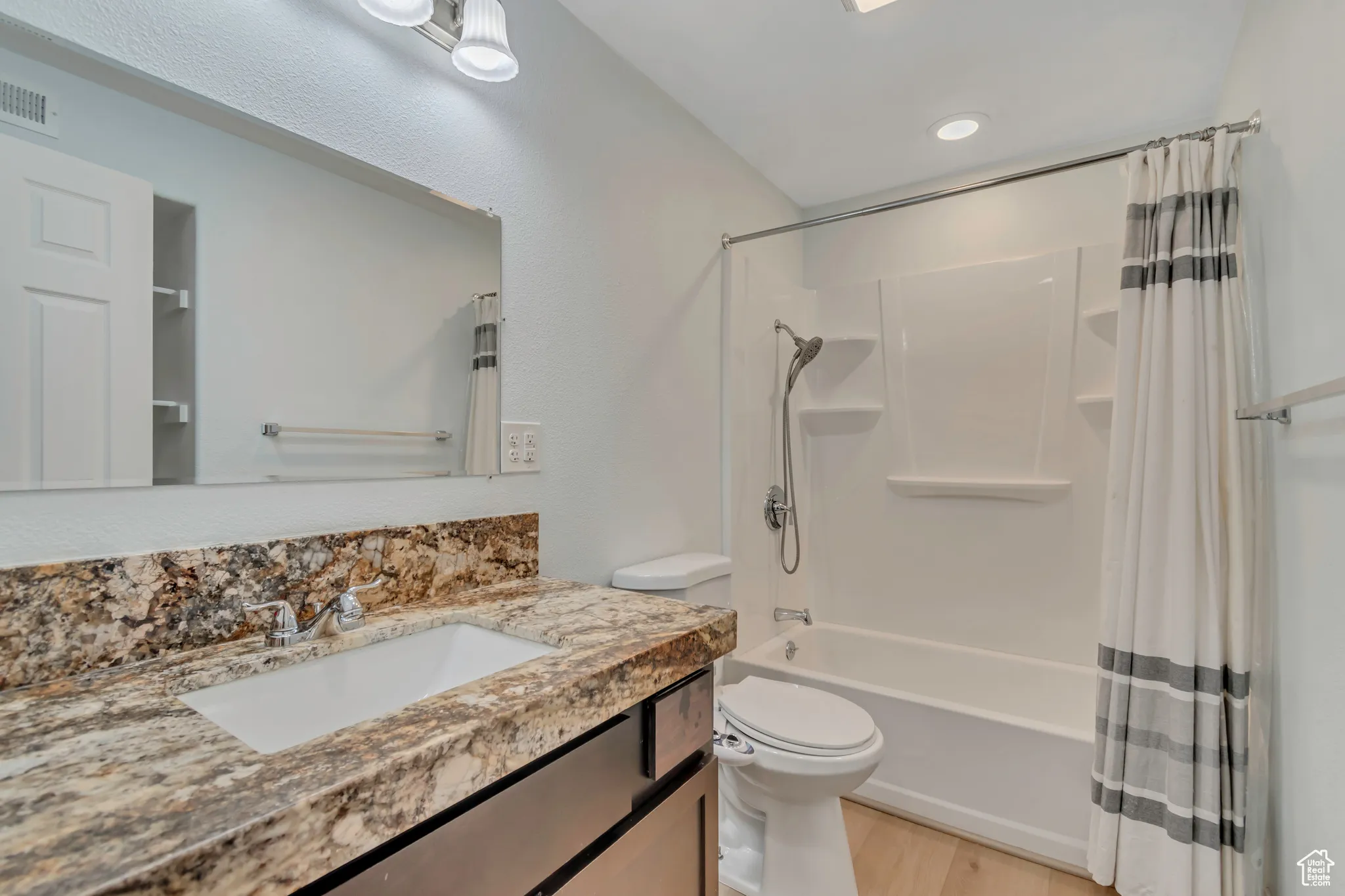 Bathroom featuring shower / bath combination with curtain, vanity, light wood-style floors, and recessed lighting