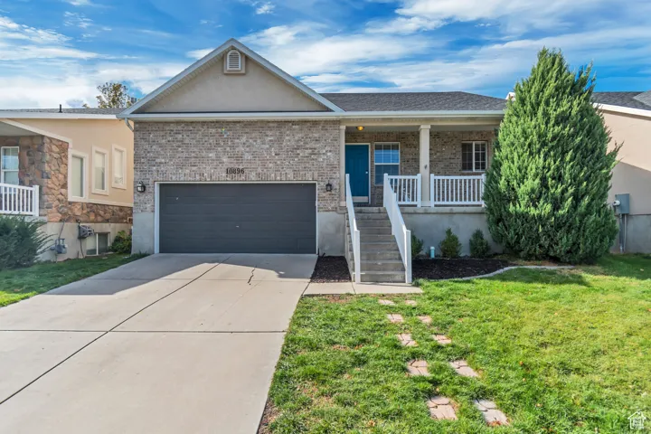 Single story home with driveway, covered porch, brick siding, stucco siding, and a front yard