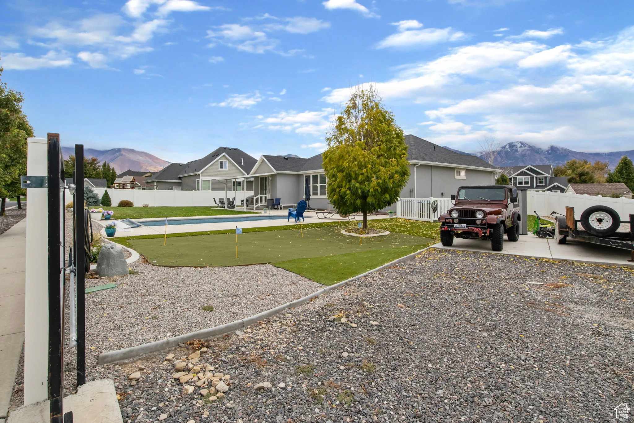 View of front of home with a fenced backyard, an area to practice putting, and a mountain view