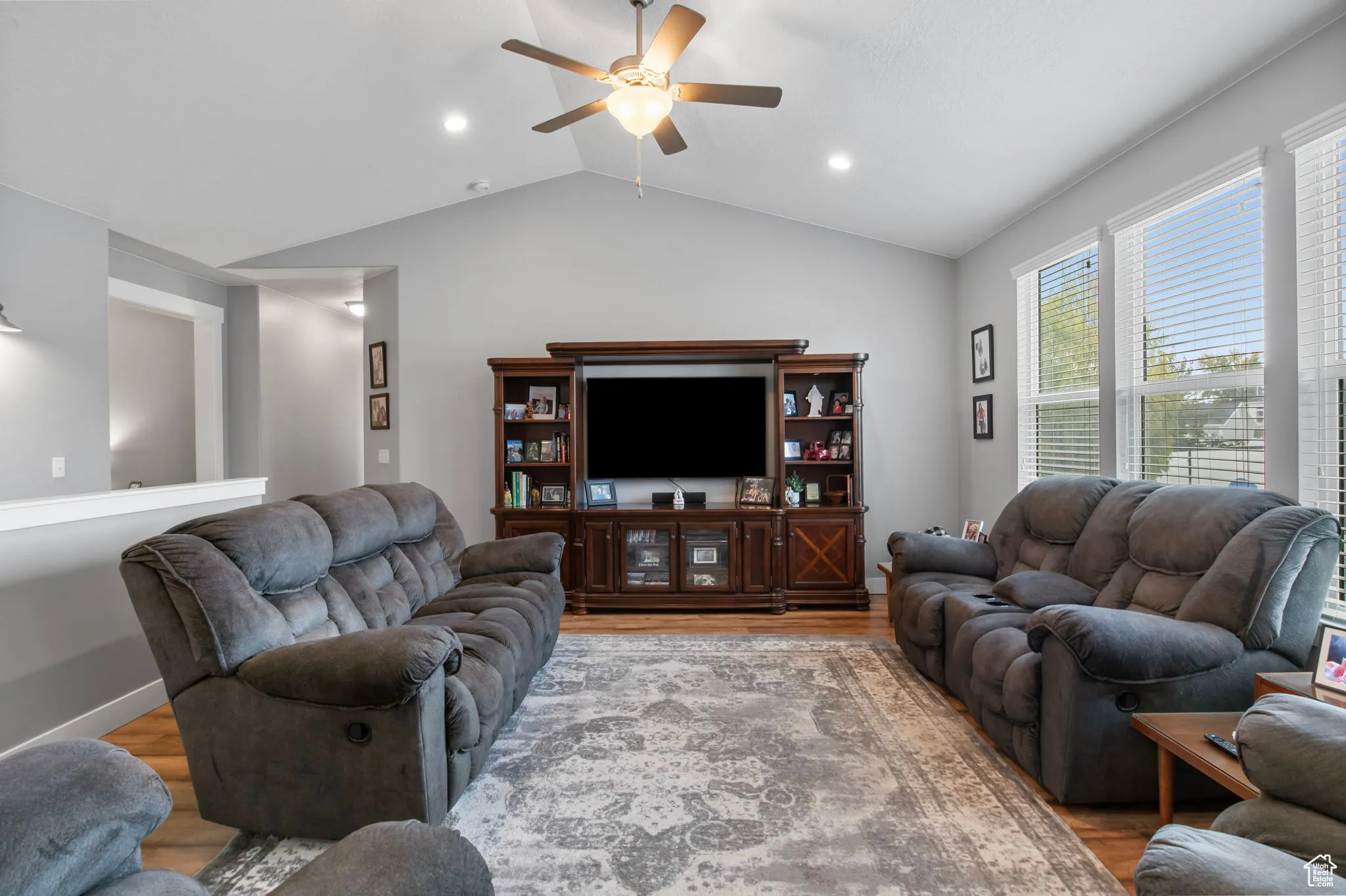 Living area with lofted ceiling, a ceiling fan, and wood finished floors