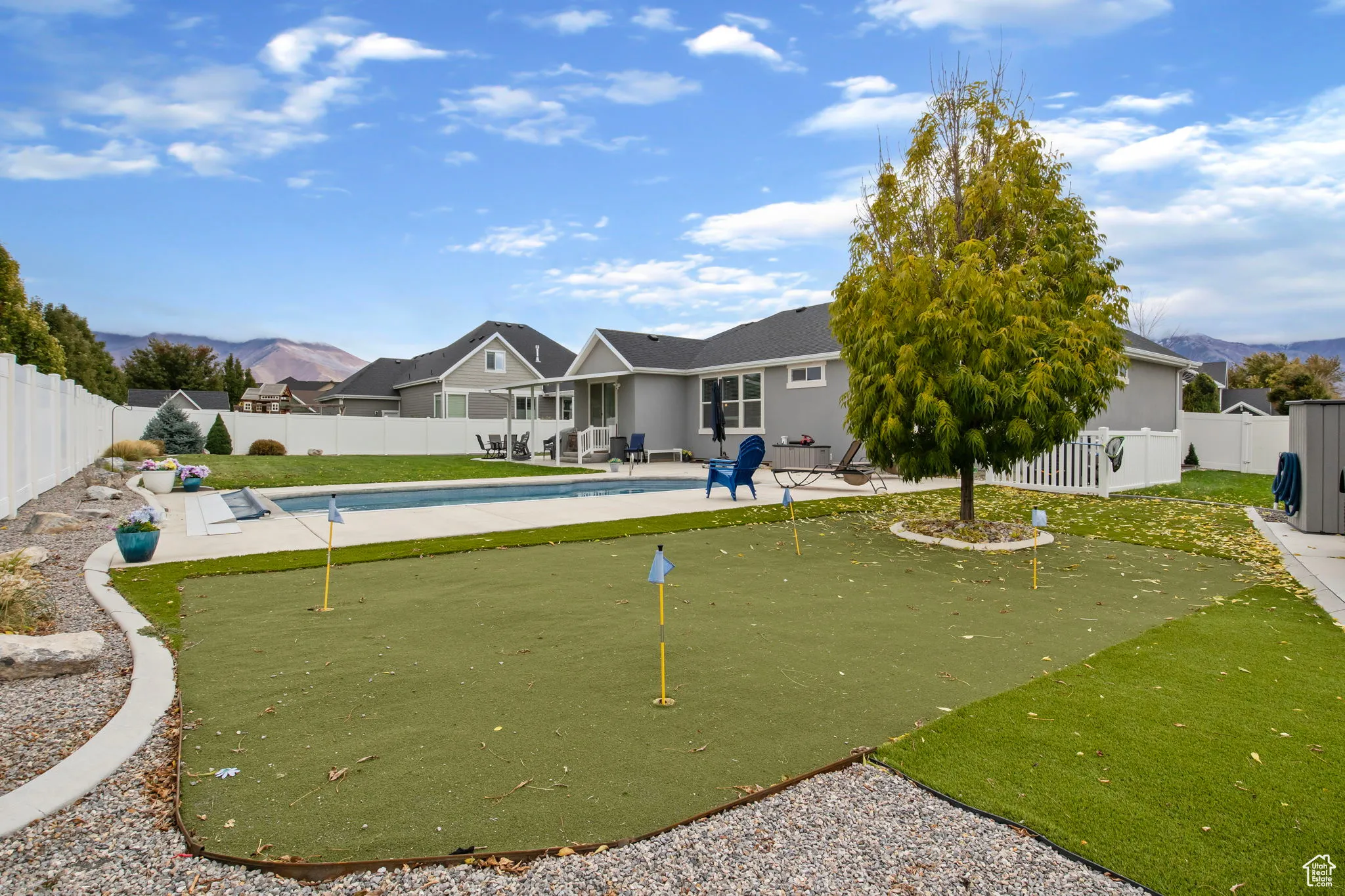 Surrounding community with a putting area, a patio, a fenced backyard, and a mountain view