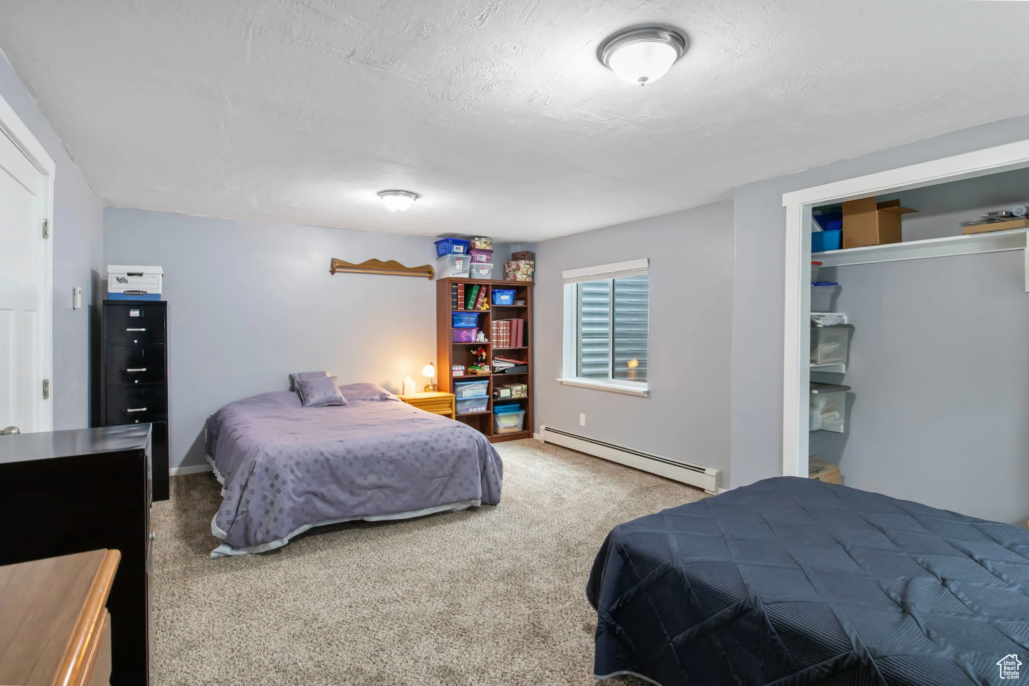 Bedroom featuring light colored carpet, a baseboard radiator, a textured ceiling, and a closet