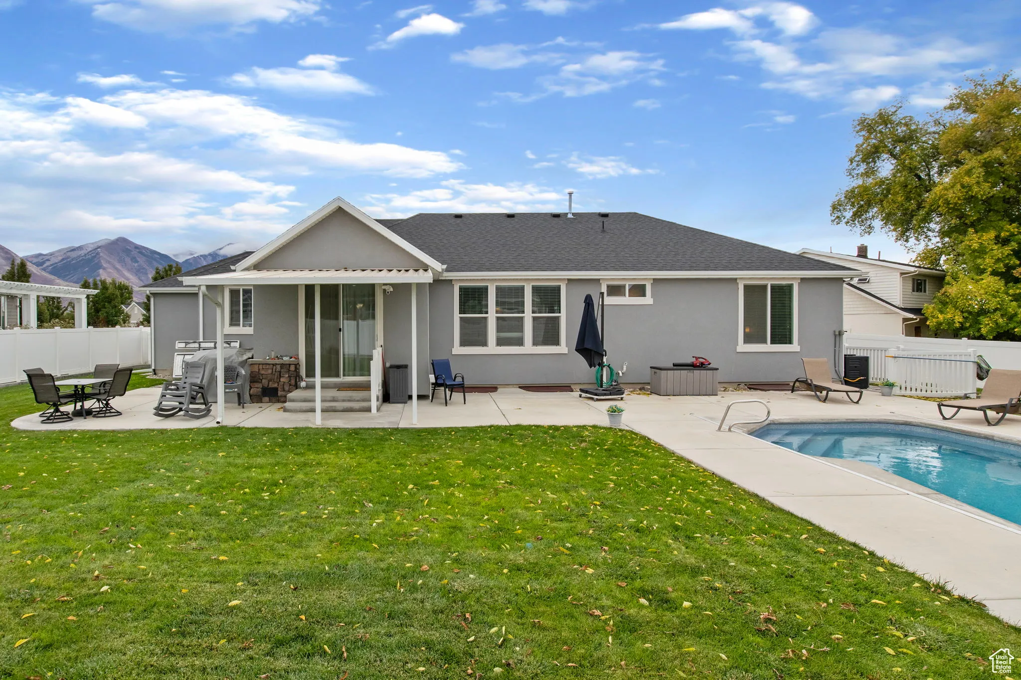 Rear view of house featuring a fenced backyard, a patio area, roof with shingles, and stucco siding