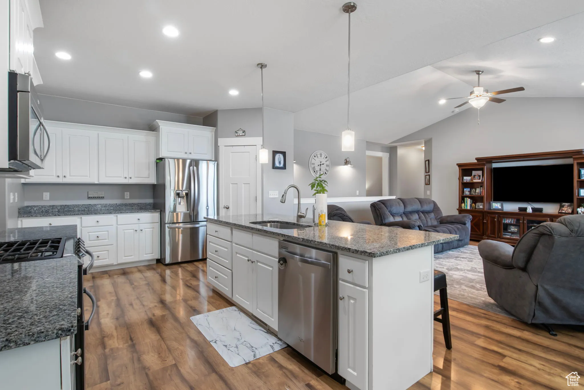 Kitchen with white cabinets, pendant lighting, stainless steel appliances, open floor plan, and vaulted ceiling