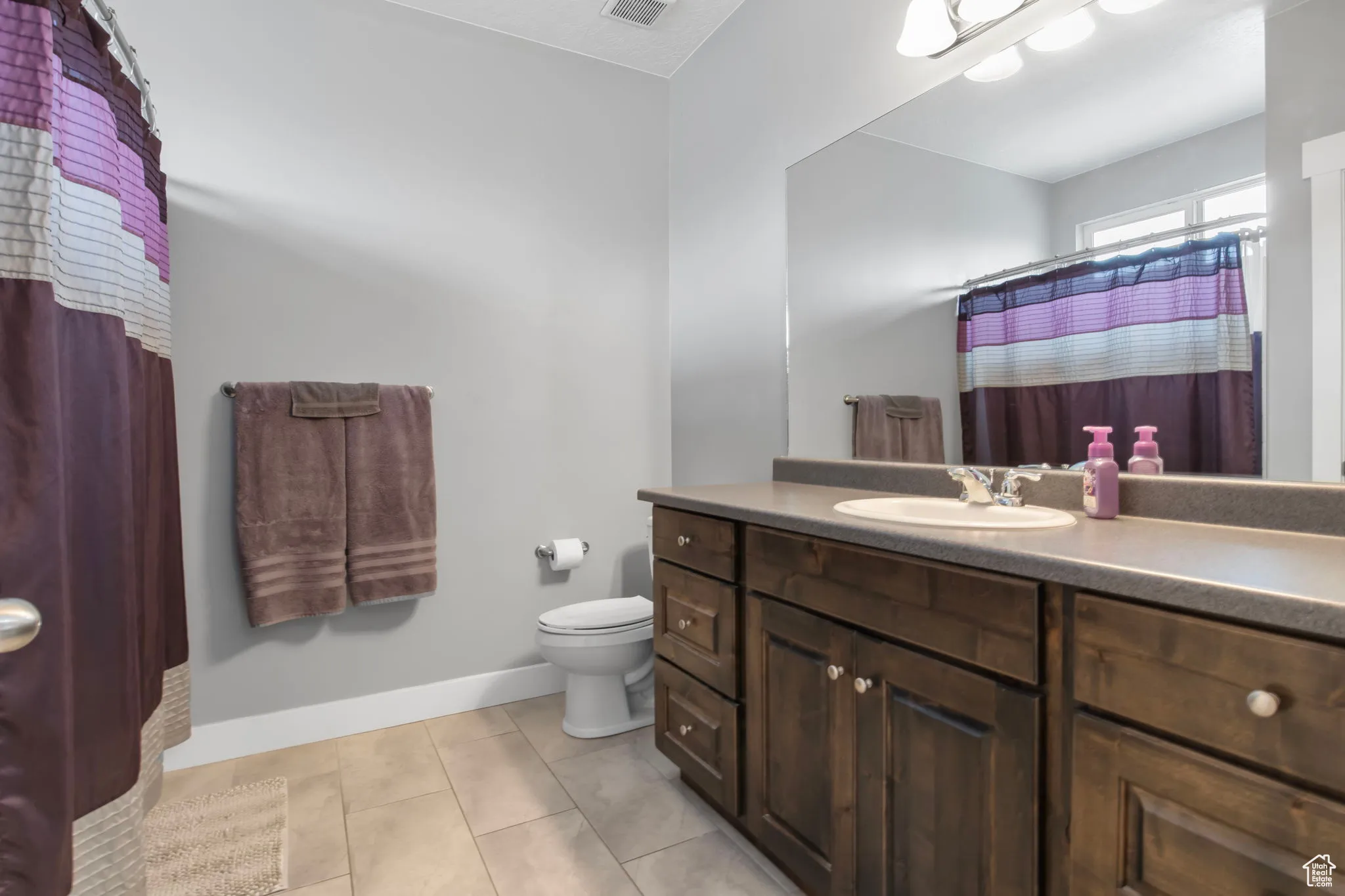 Primary bathroom with light tile patterned floors, vanity, and a shower with shower curtain