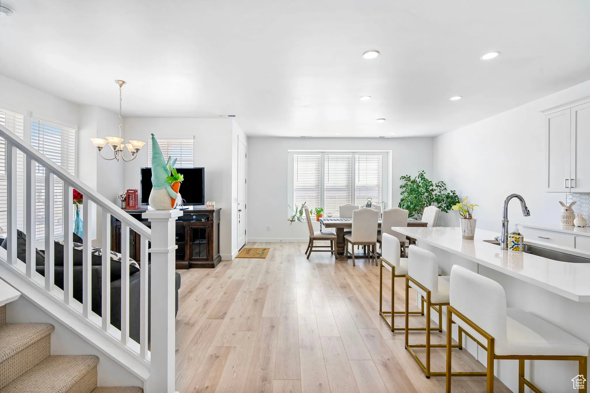 Kitchen with light wood-style flooring, a breakfast bar, hanging light fixtures, white cabinetry, and recessed lighting