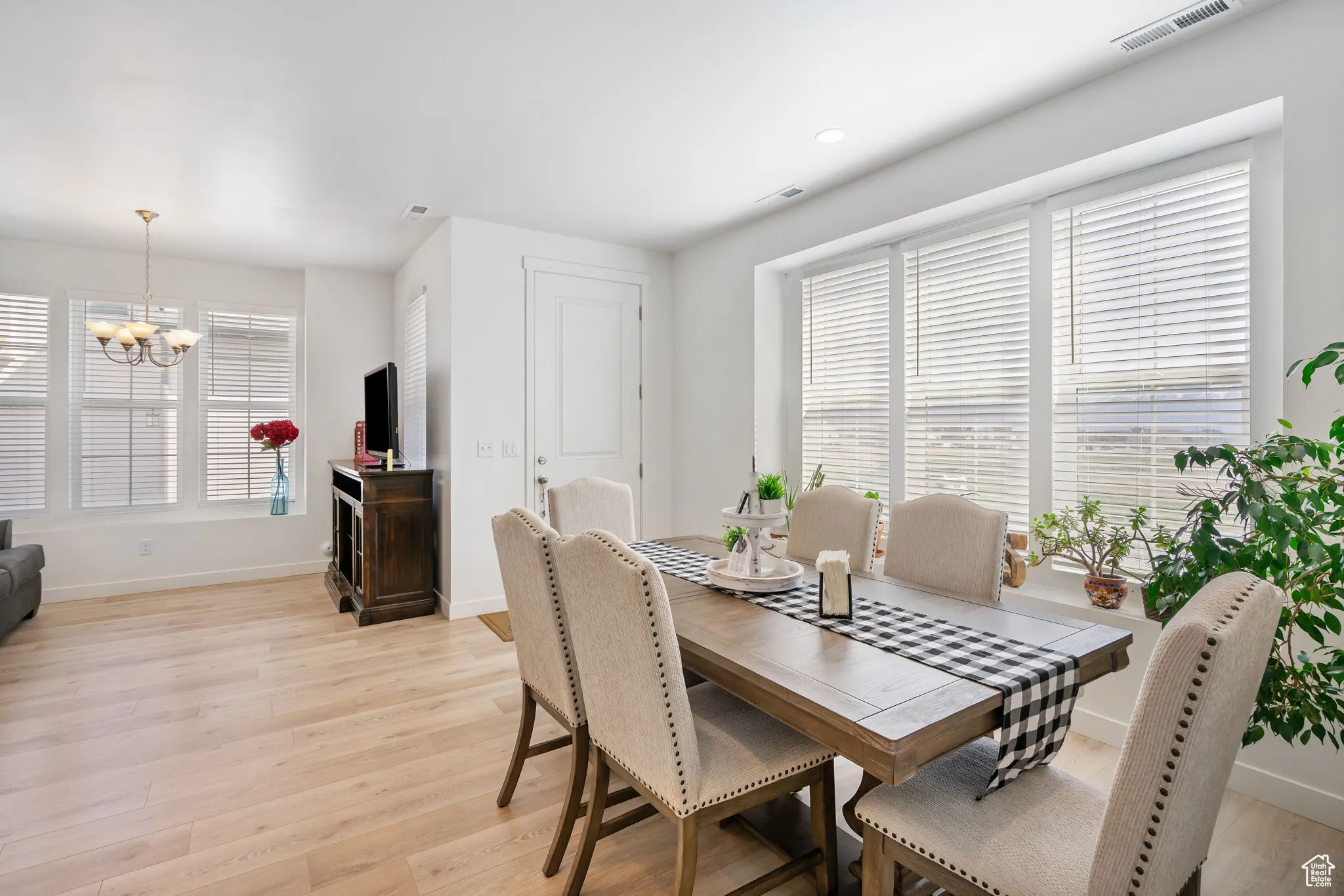 Dining area with light wood finished floors, a chandelier, and recessed lighting