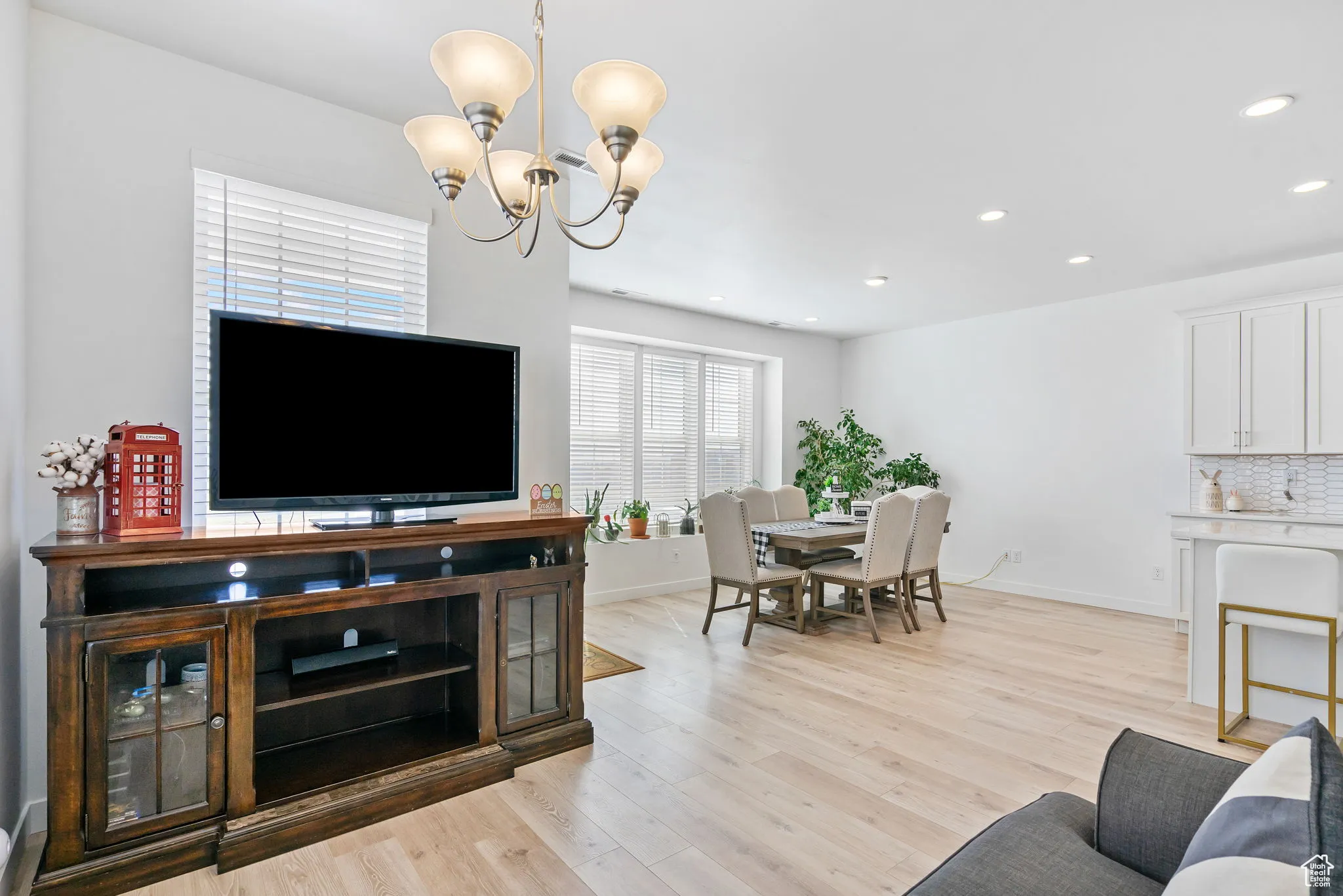 Living area with light wood-style floors, recessed lighting, and a chandelier