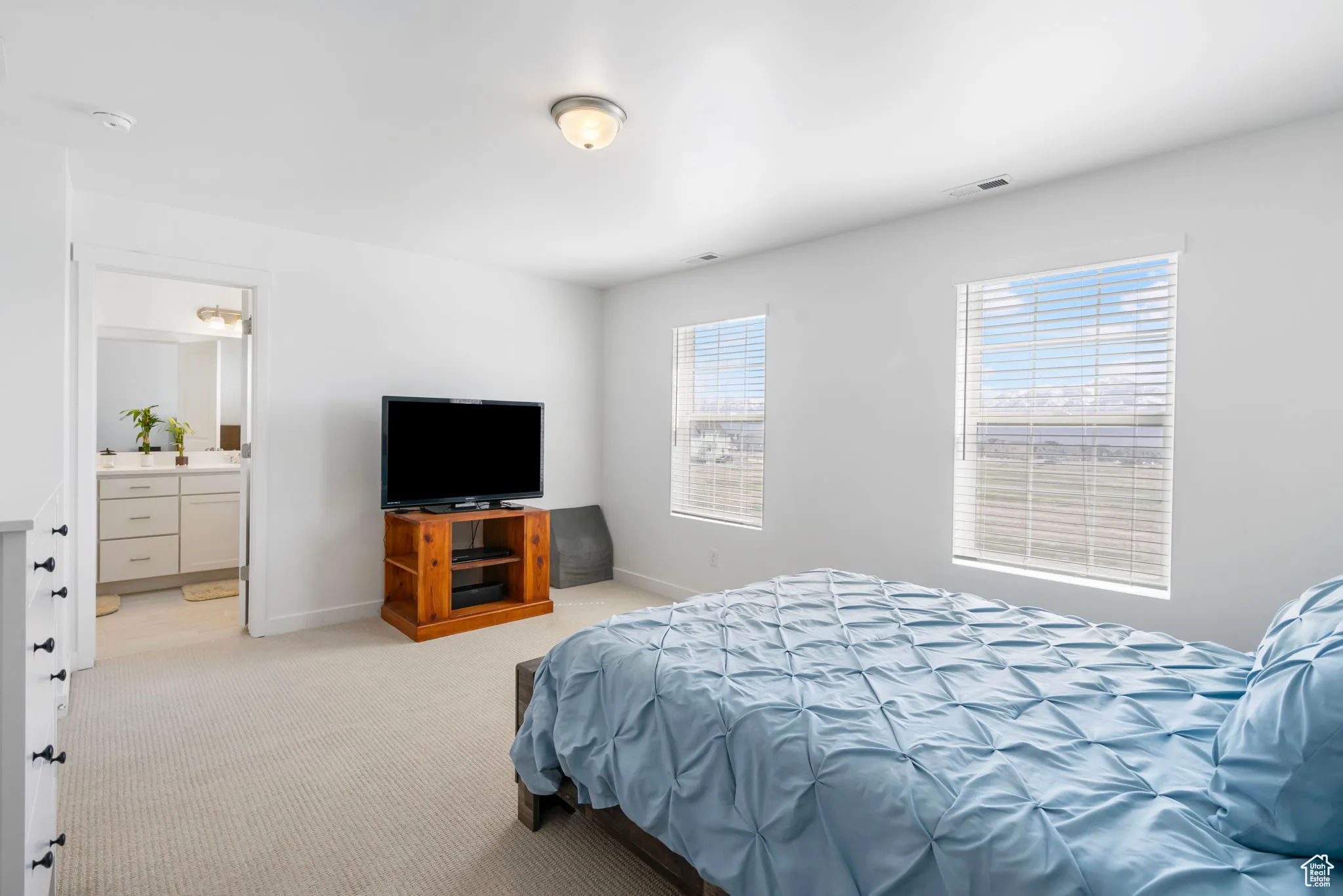 Bedroom featuring light colored carpet and ensuite bath