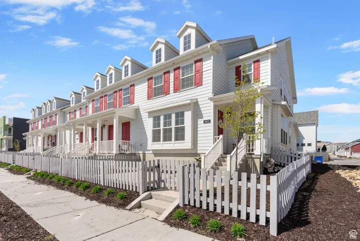 Colonial inspired home featuring a residential view, covered porch, and a fenced front yard