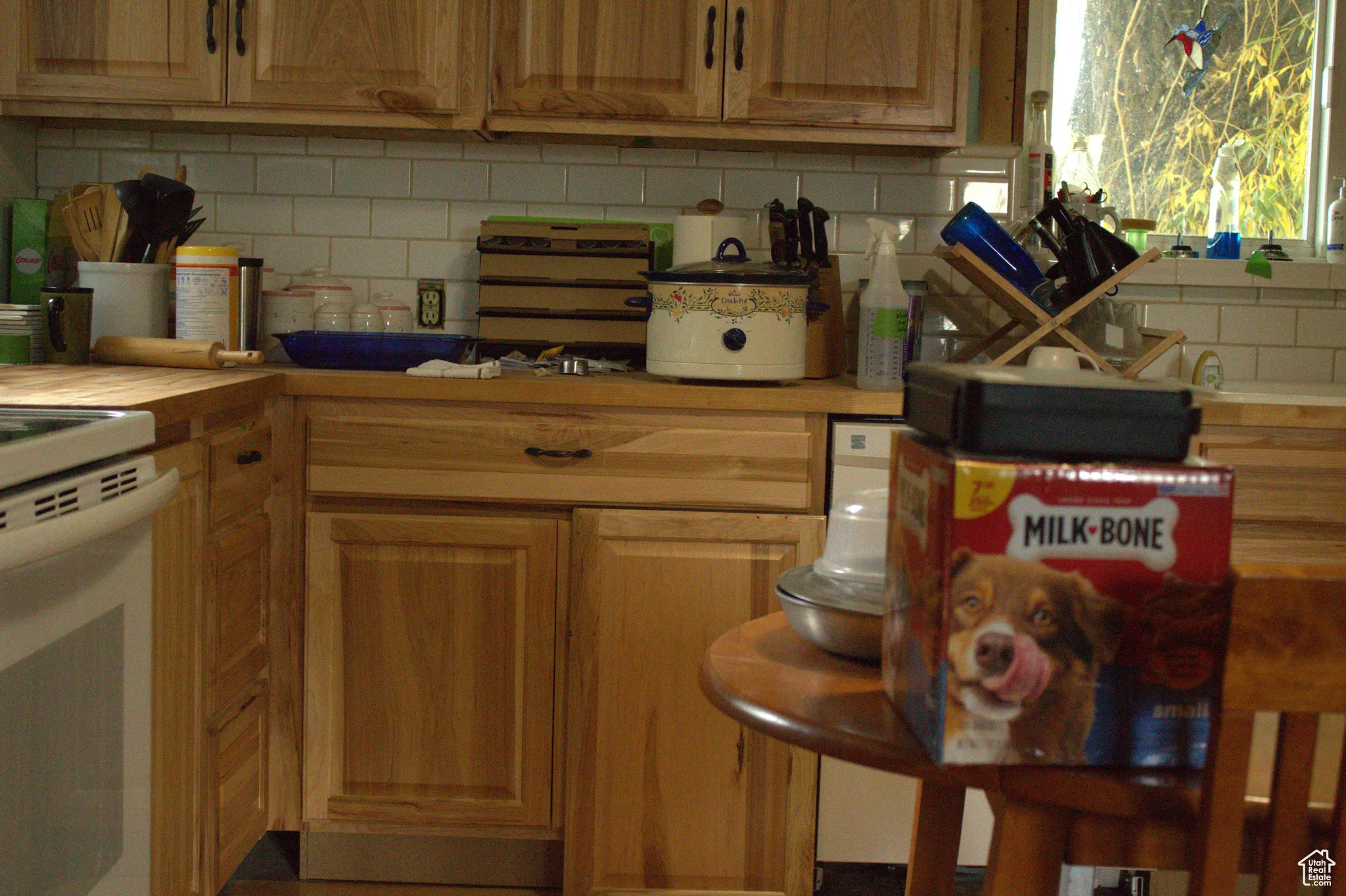 Kitchen with backsplash, light countertops, white electric range, and brown cabinets