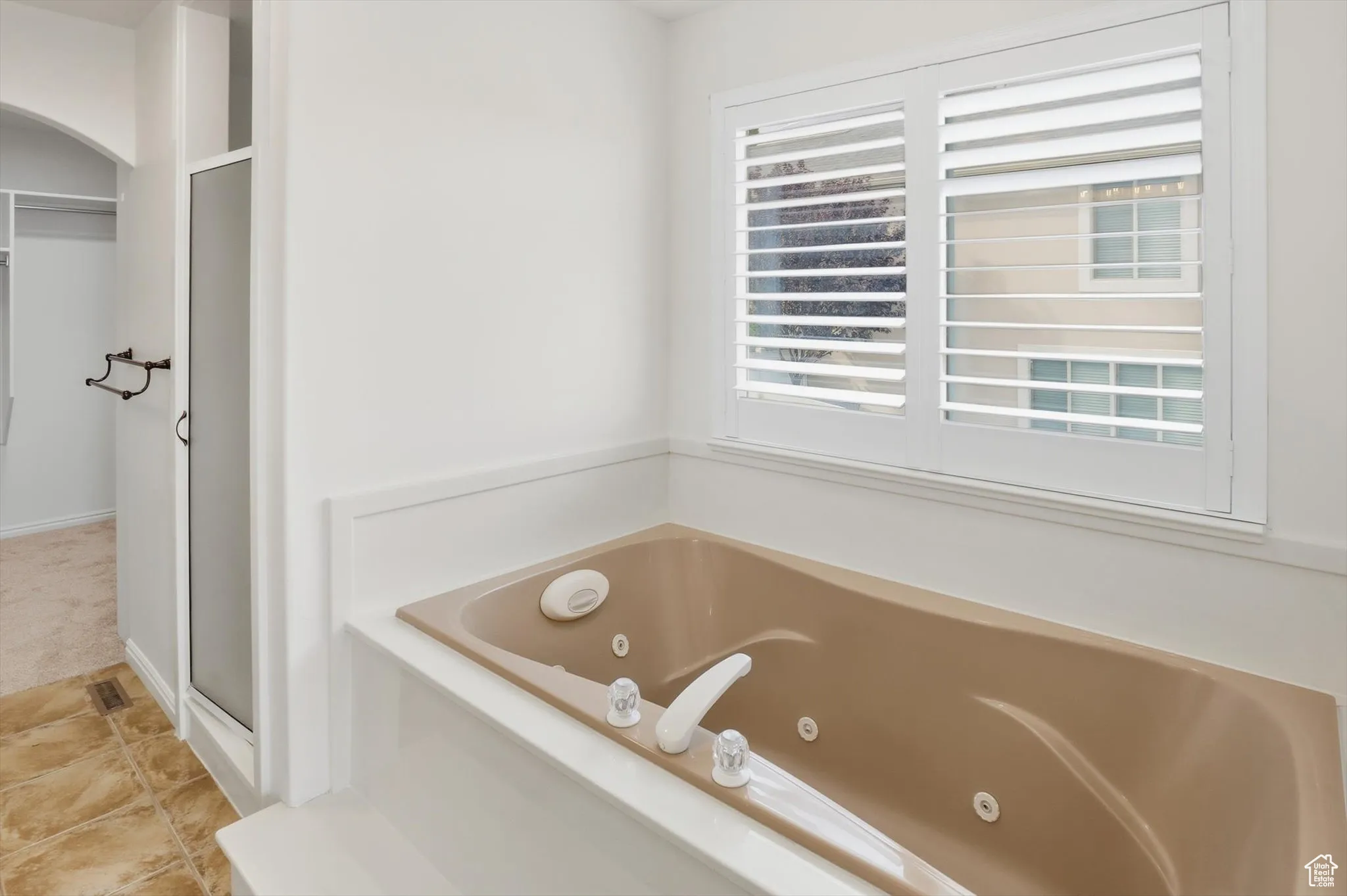 Full bath with a shower stall, a jetted tub, a spacious closet, and light tile patterned floors
