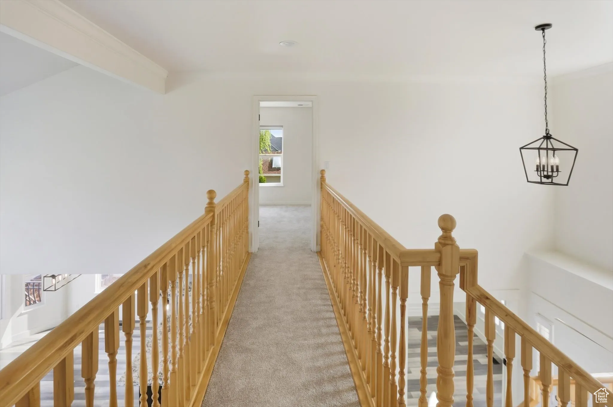 Corridor featuring an upstairs landing, carpet, ornamental molding, and a chandelier
