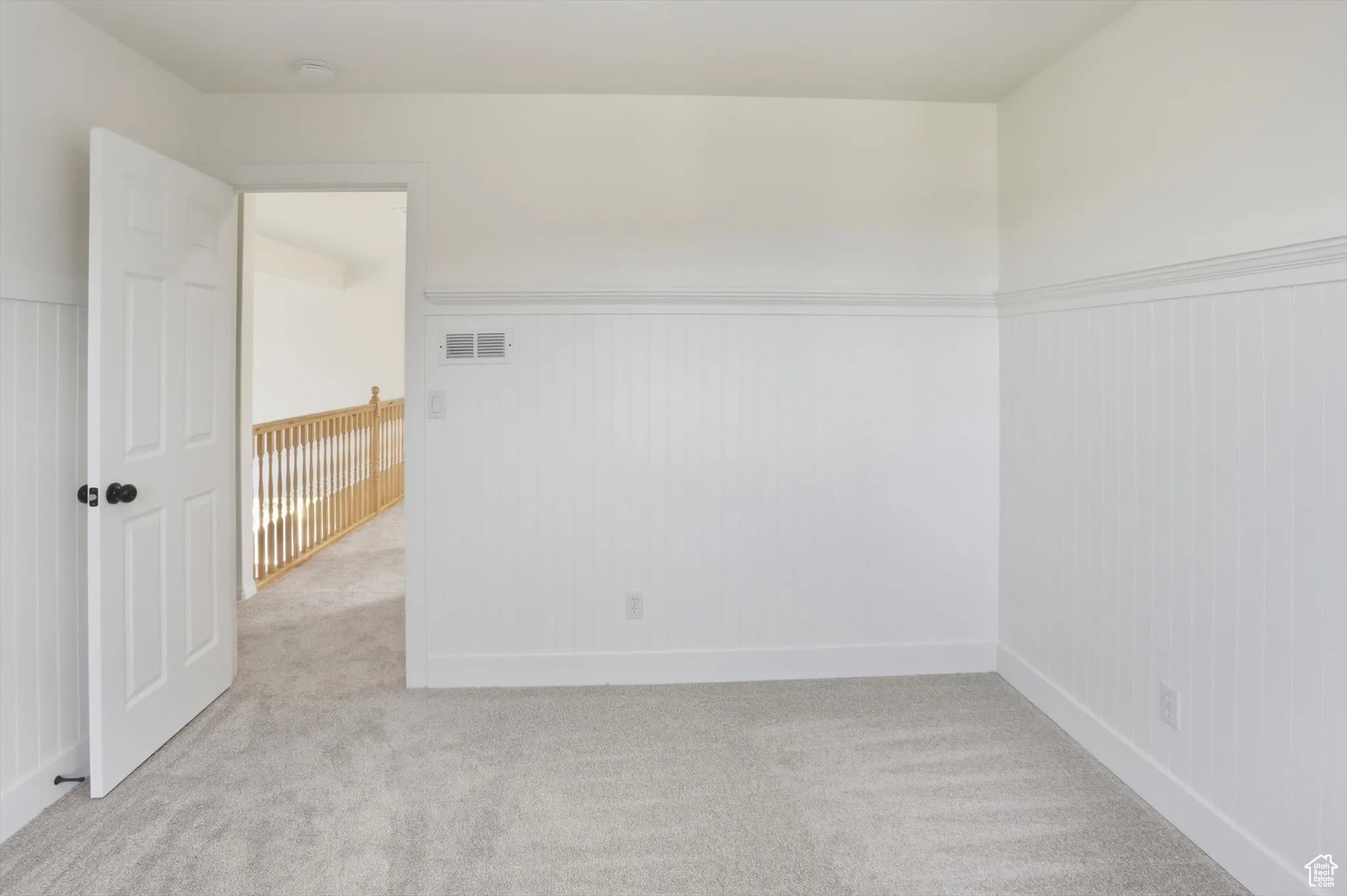 Spare room featuring light colored carpet and wainscoting