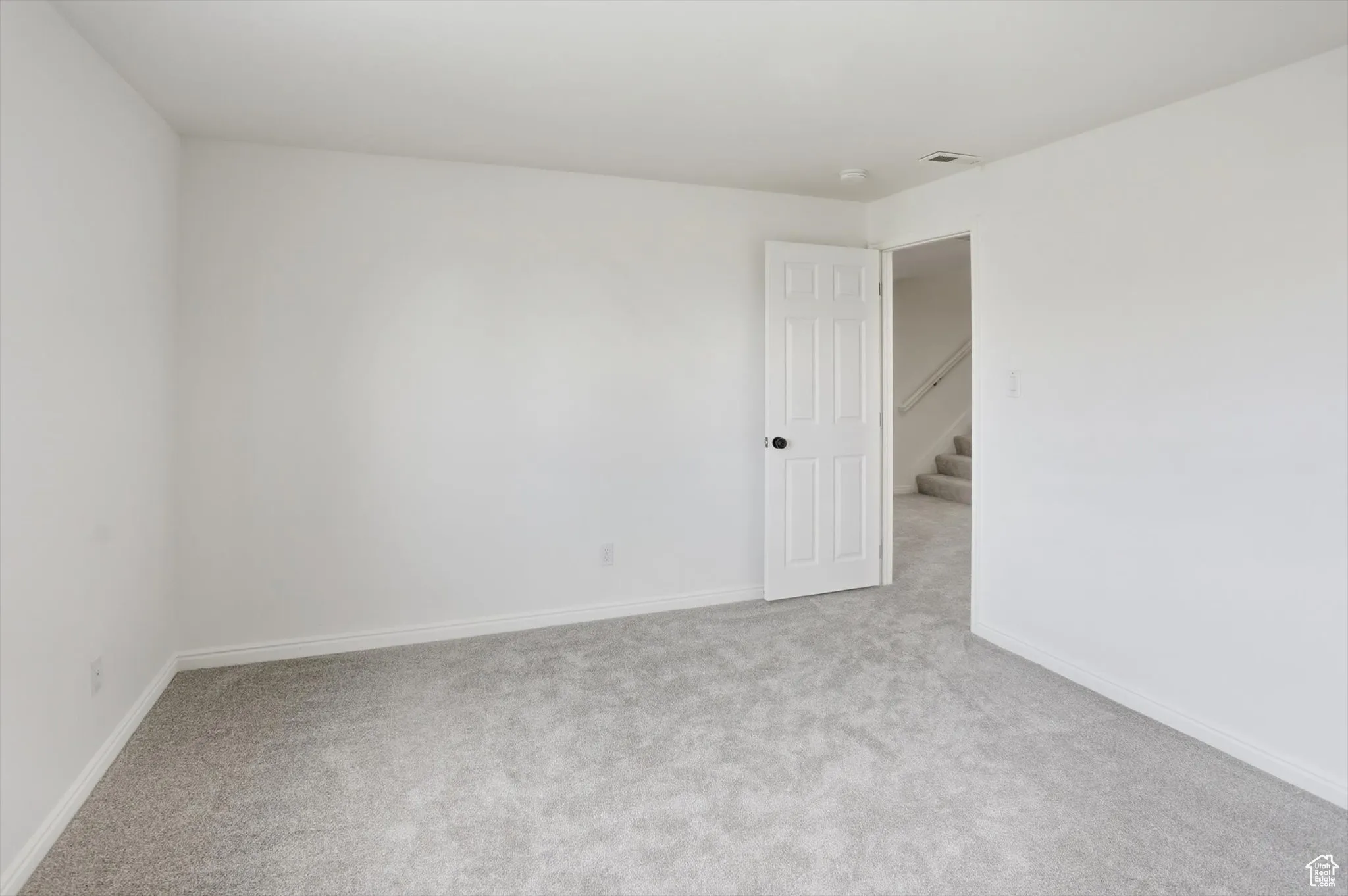 Empty room featuring light colored carpet and stairs