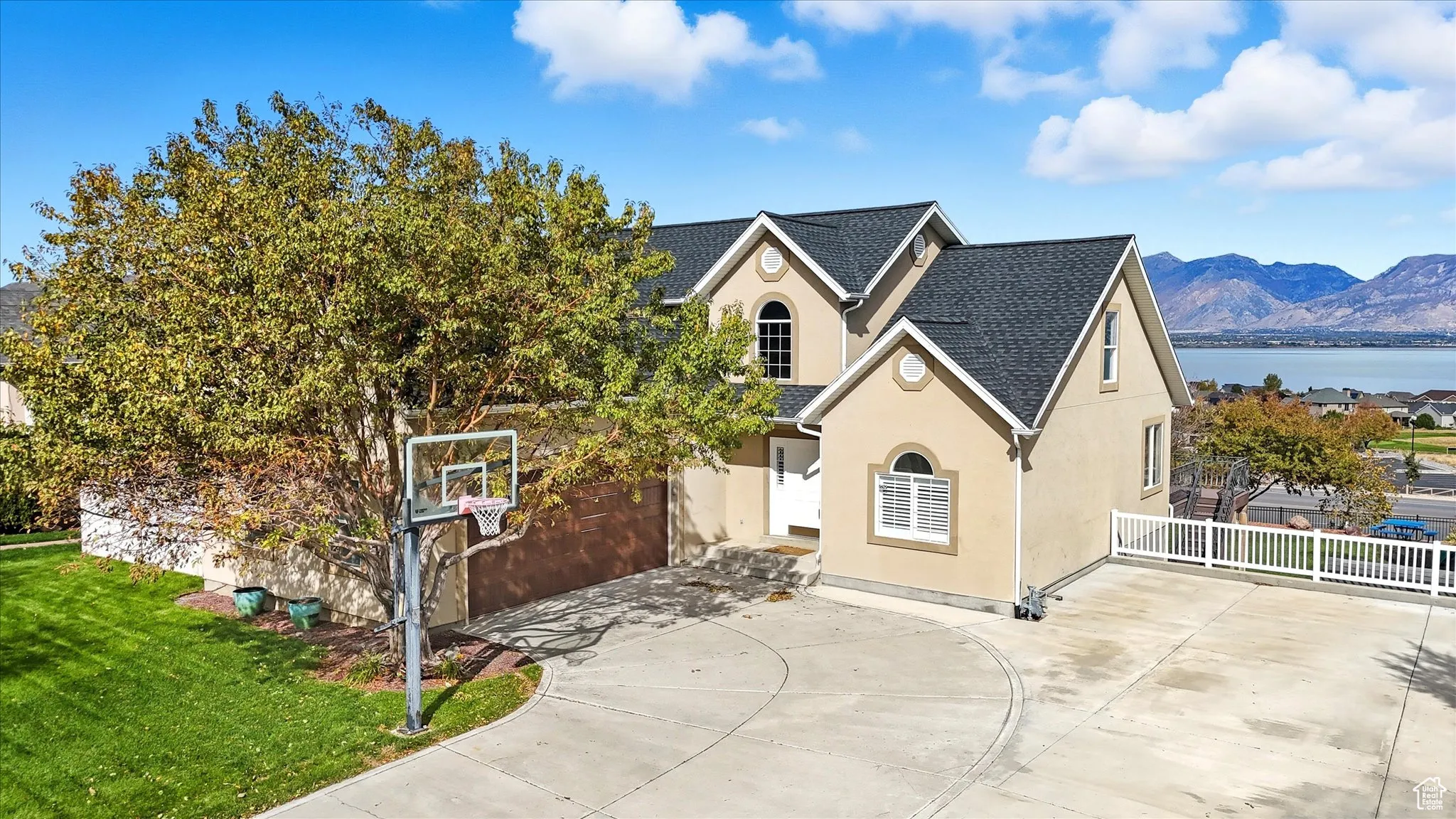 View of front of home with stucco siding, concrete driveway, a shingled roof, a garage, and a water and mountain view