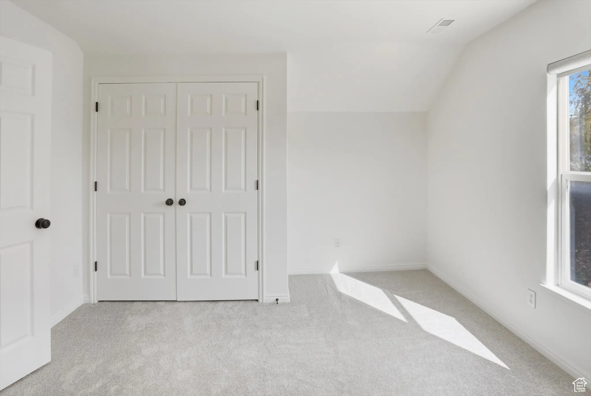 Unfurnished bedroom featuring carpet flooring, vaulted ceiling, and a closet