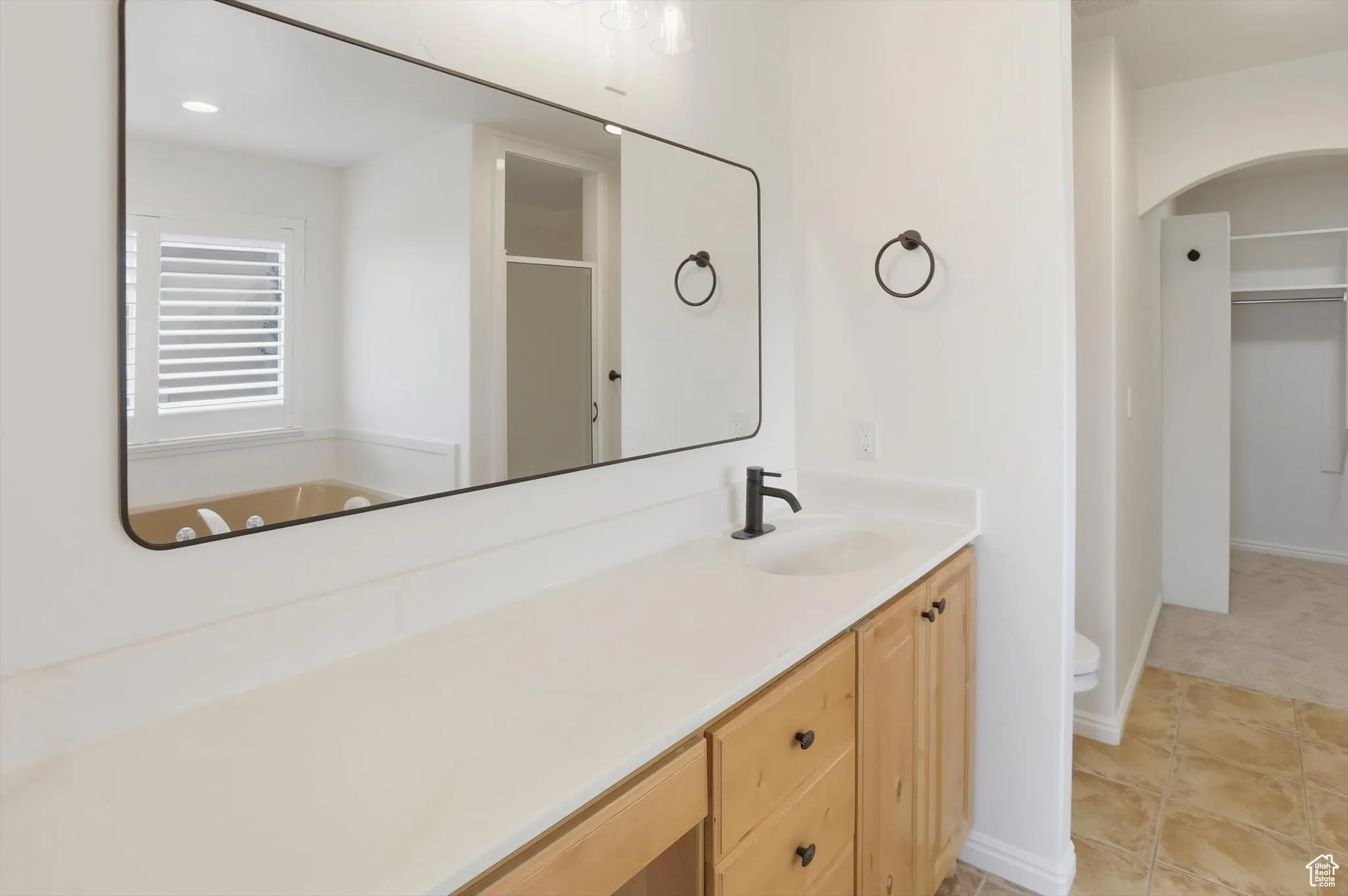 Bathroom with a stall shower, vanity, a walk in closet, light tile patterned floors, and recessed lighting