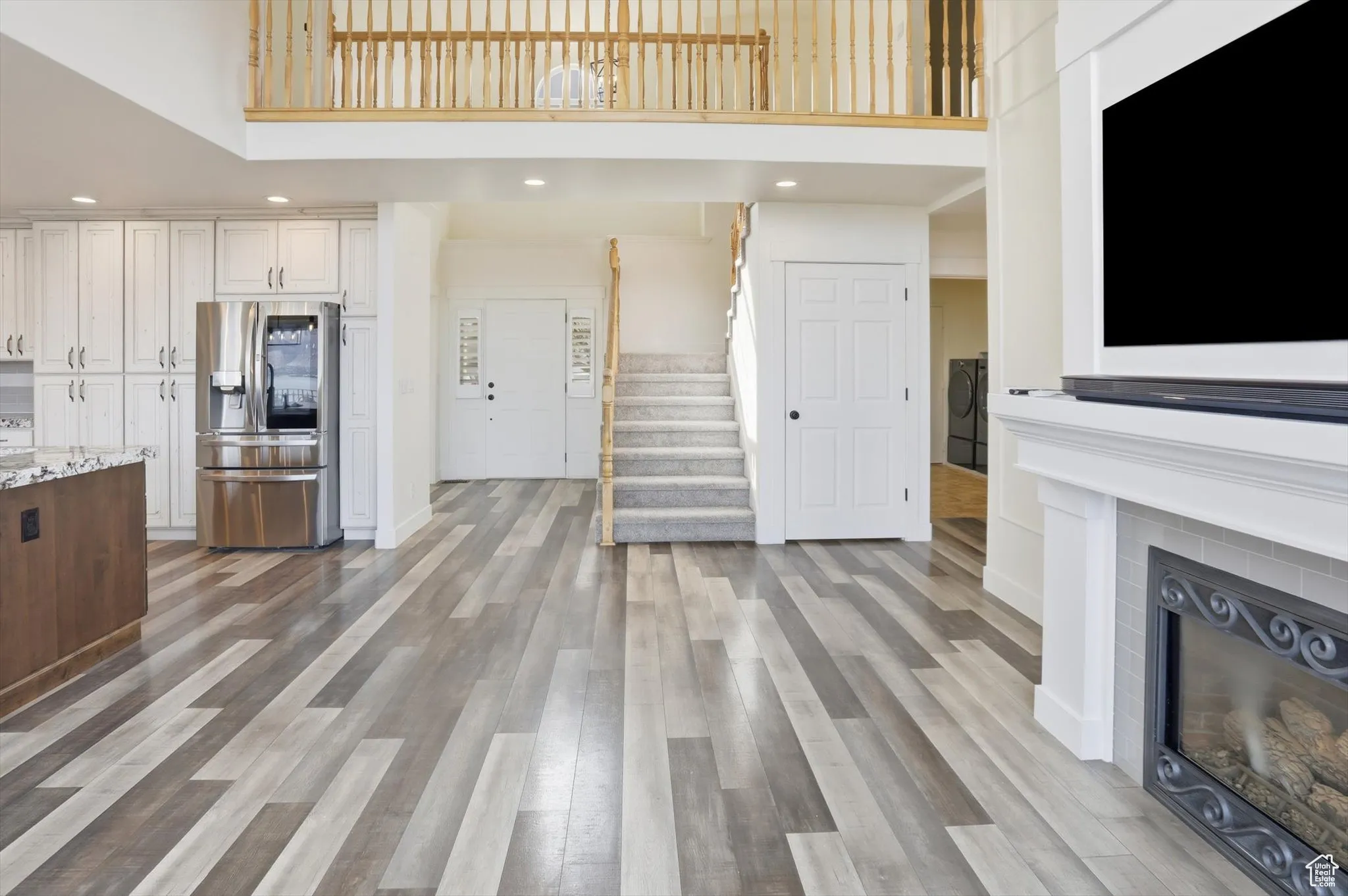 Unfurnished living room featuring recessed lighting, stairs, a high ceiling, a glass covered fireplace, and dark wood-type flooring