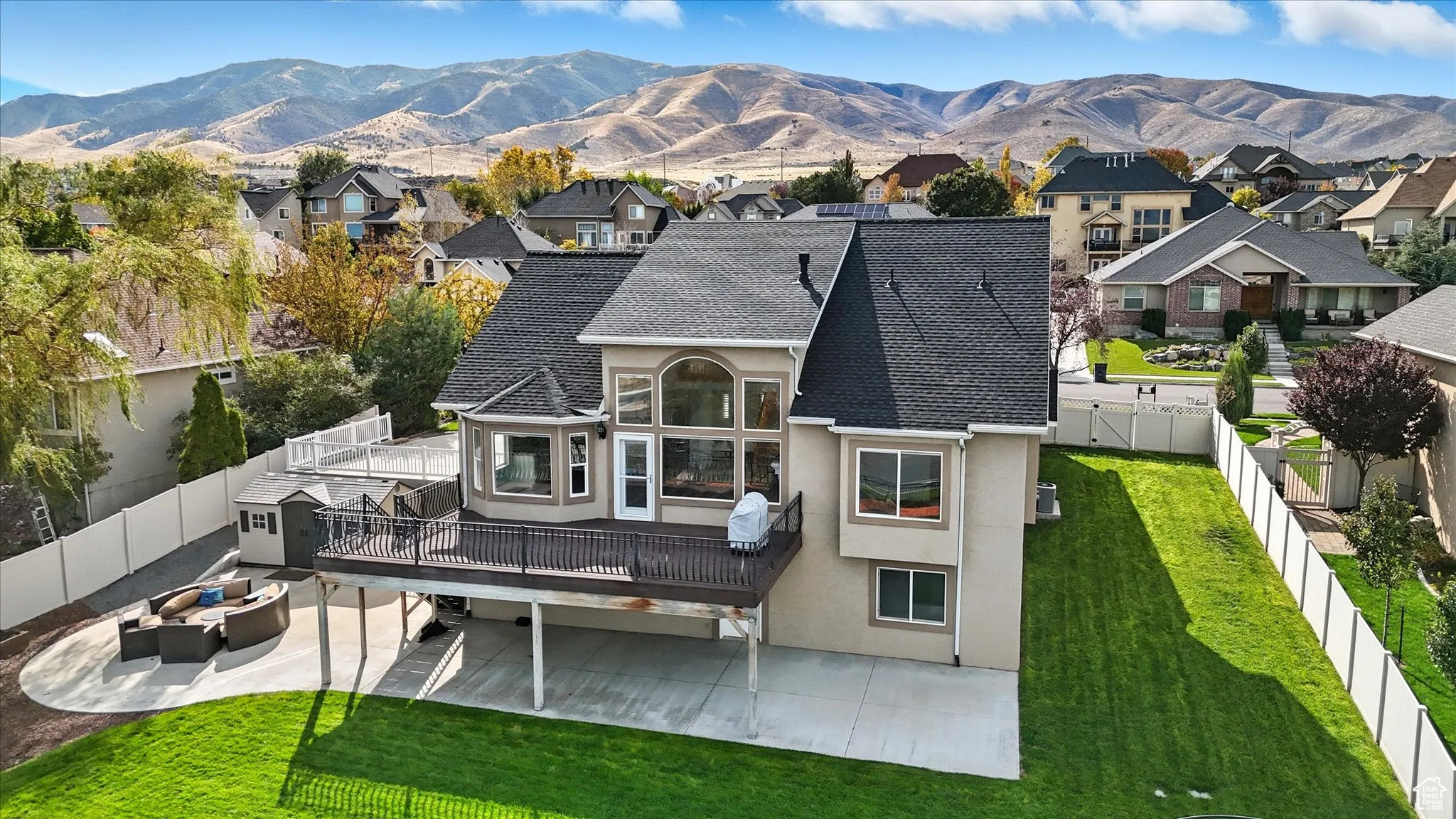 Rear view of house with a fenced backyard, stucco siding, a shingled roof, and a patio area