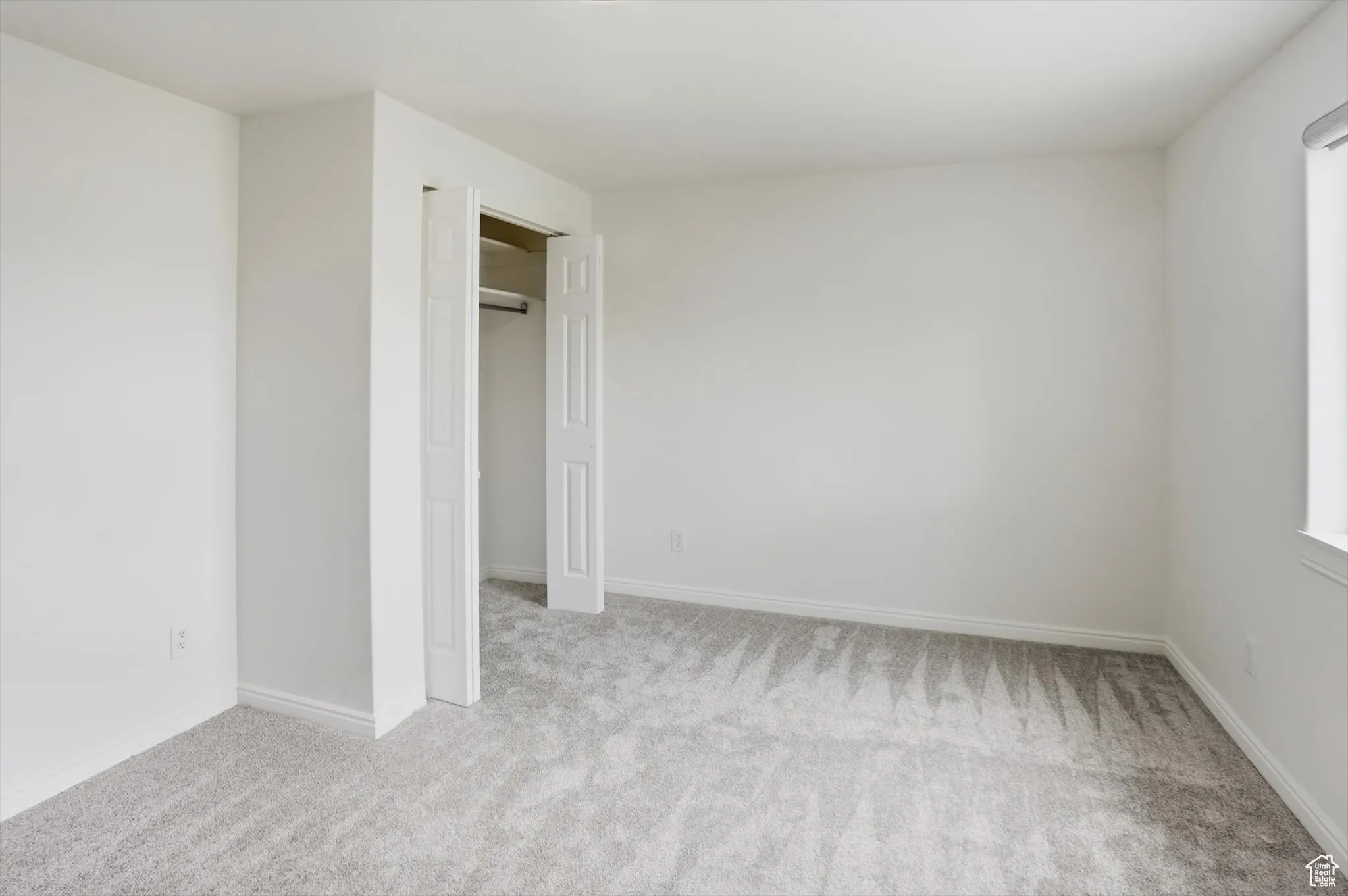 Unfurnished bedroom with light carpet and a closet