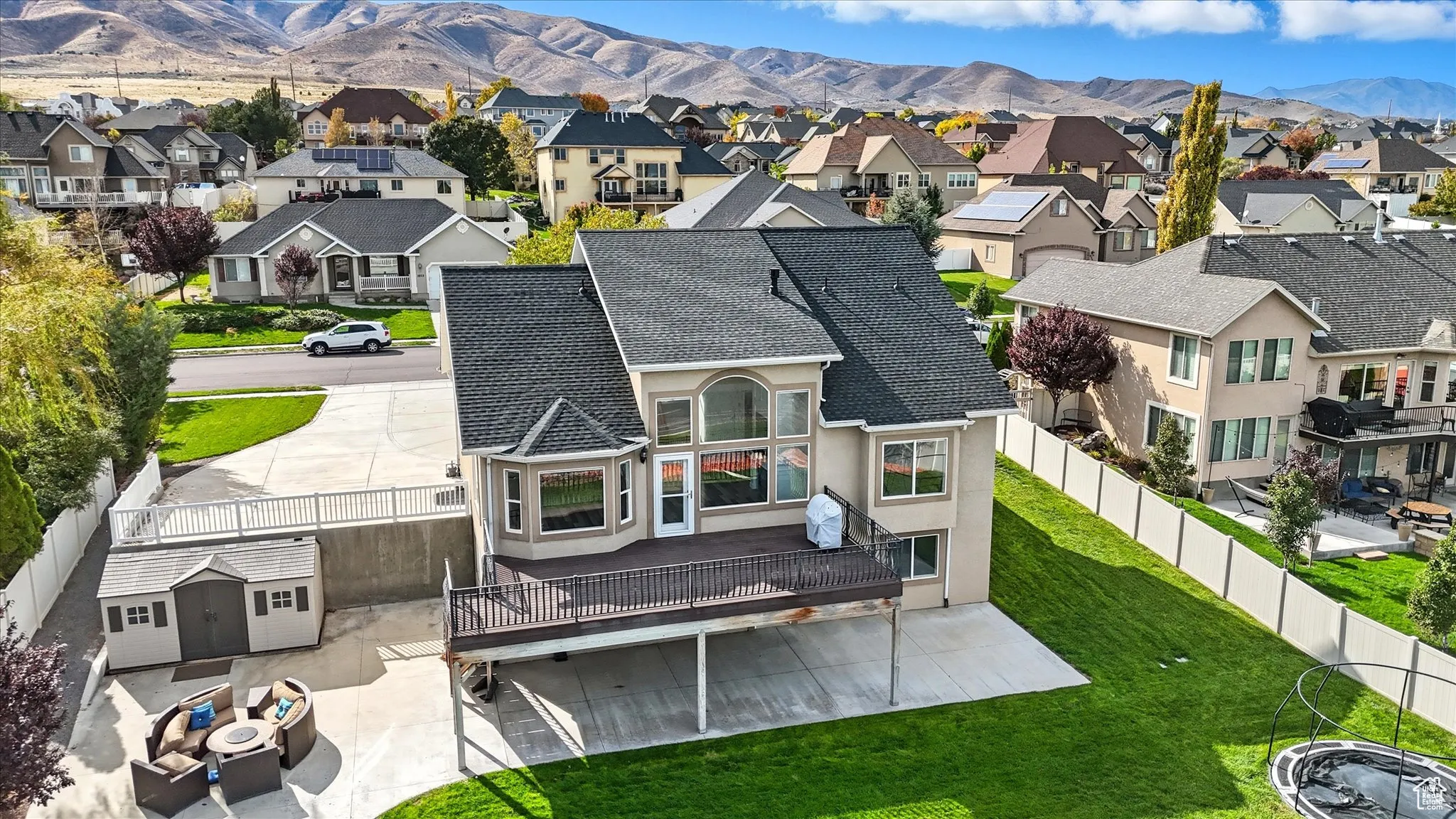 Rear view of house with stucco siding, a mountain view, a patio area, a shingled roof, and a residential view