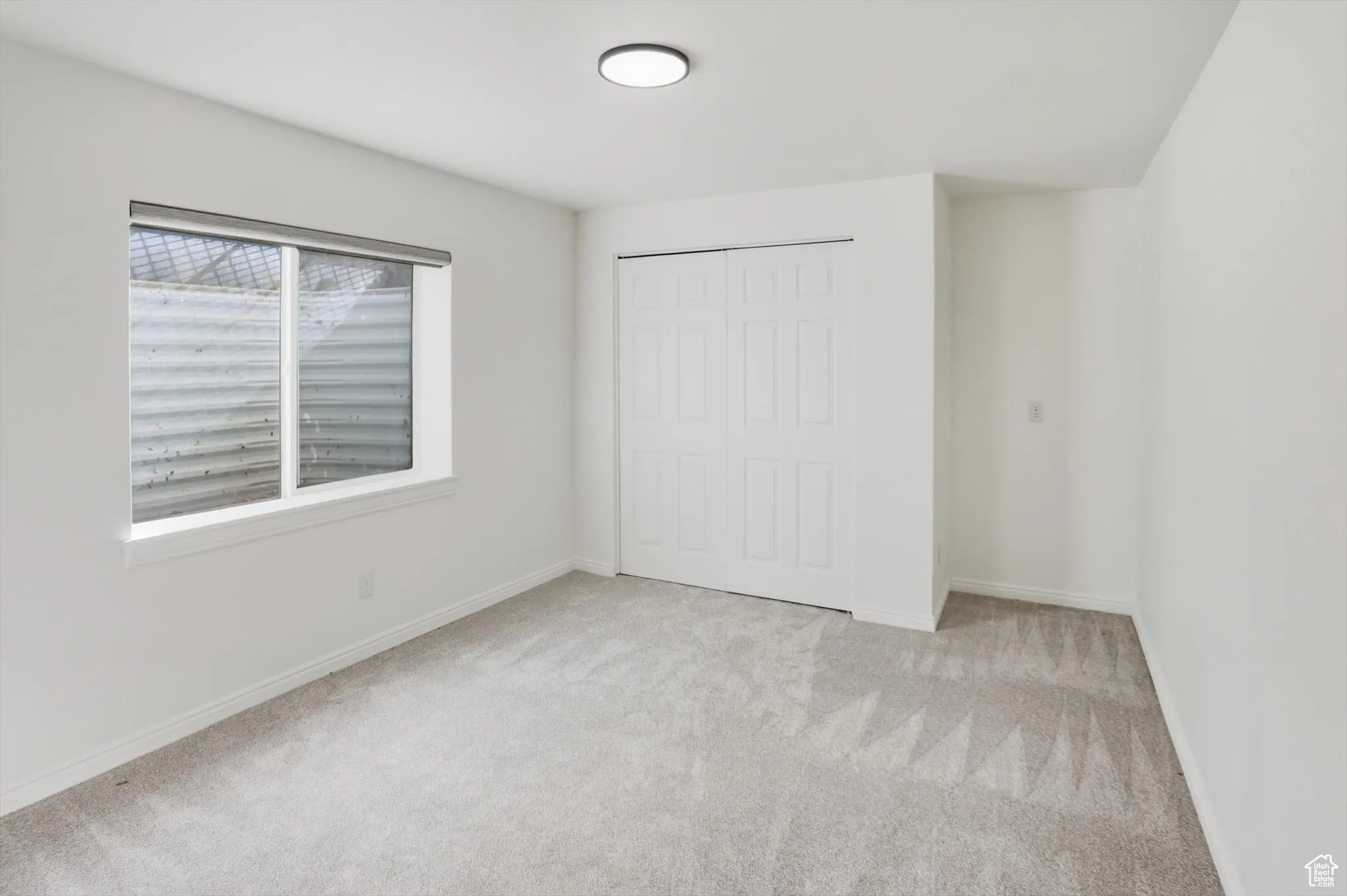Unfurnished bedroom featuring light colored carpet and a closet