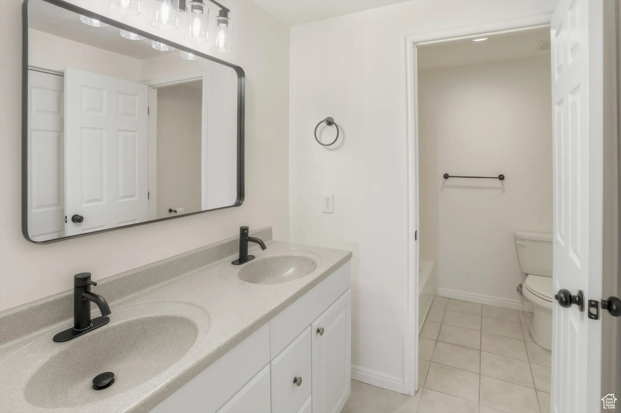 Full bath featuring light tile patterned floors and double vanity